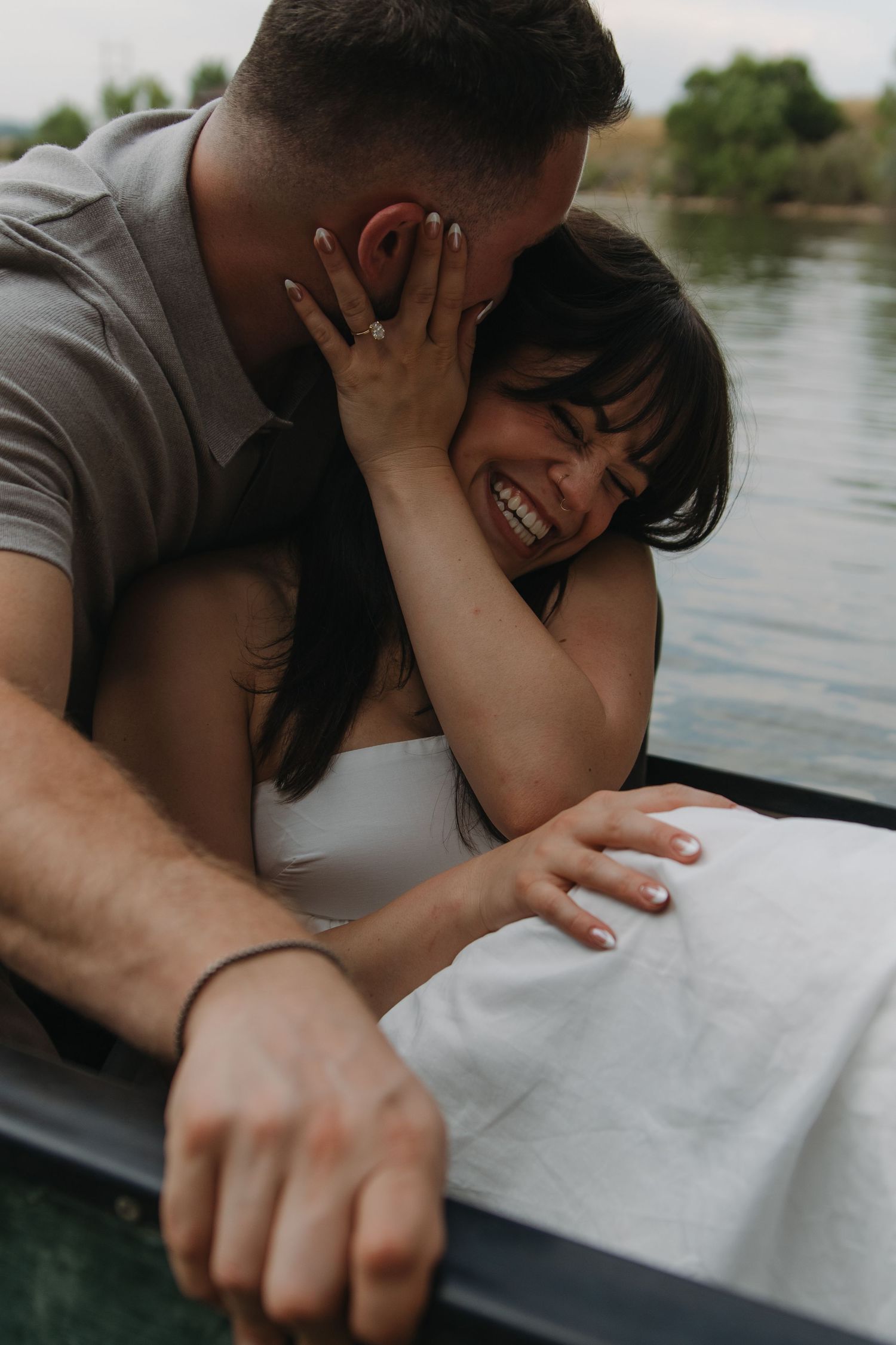 Tender moments captured between a couple cuddling in a boat on calm waters.