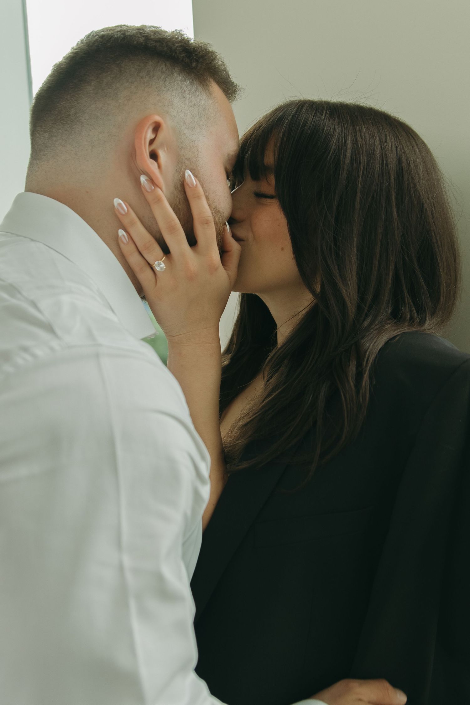 Intimate close-up portrait of couple against neutral wall background.