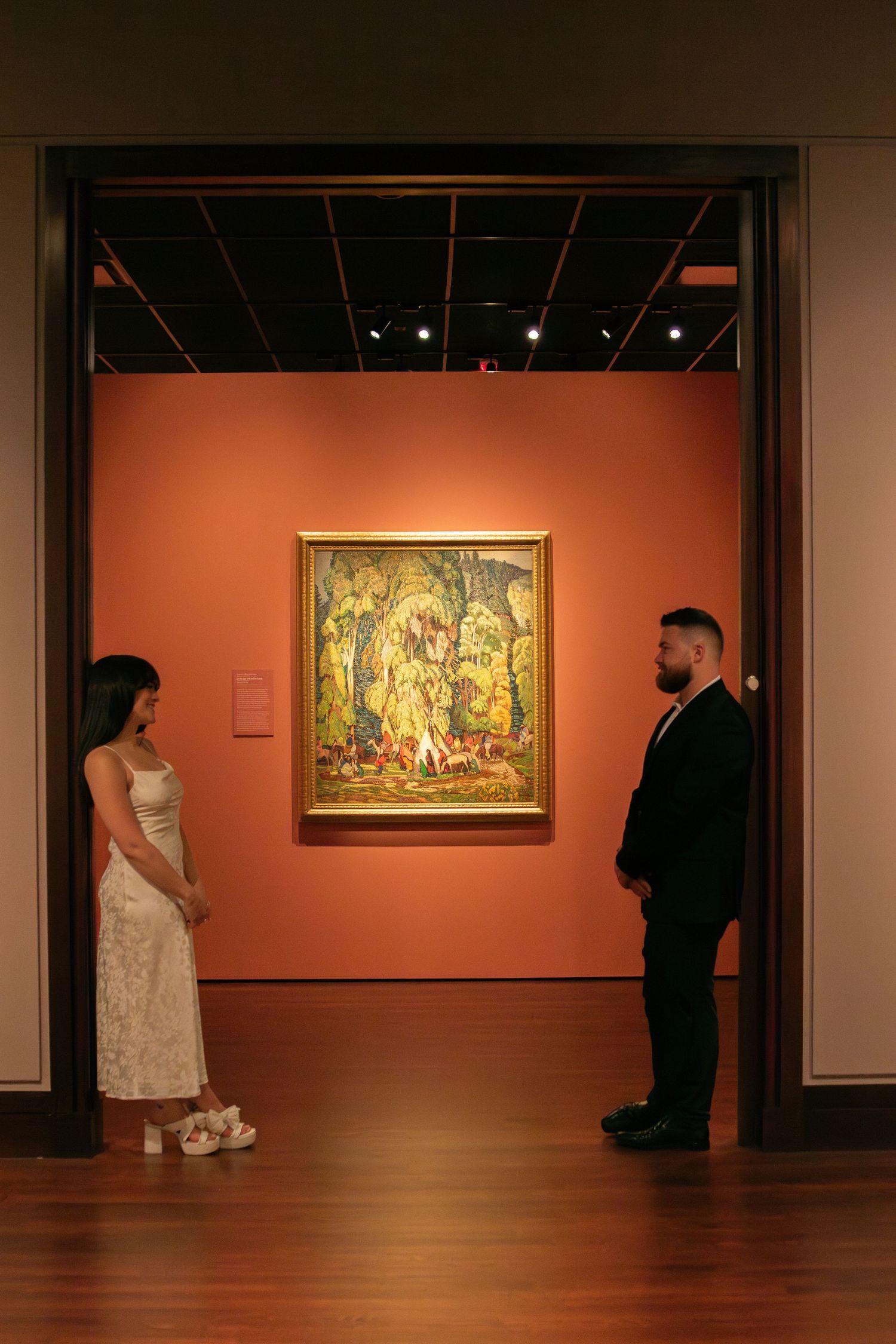 Art museum gallery interior with orange walls and classical paintings on display.