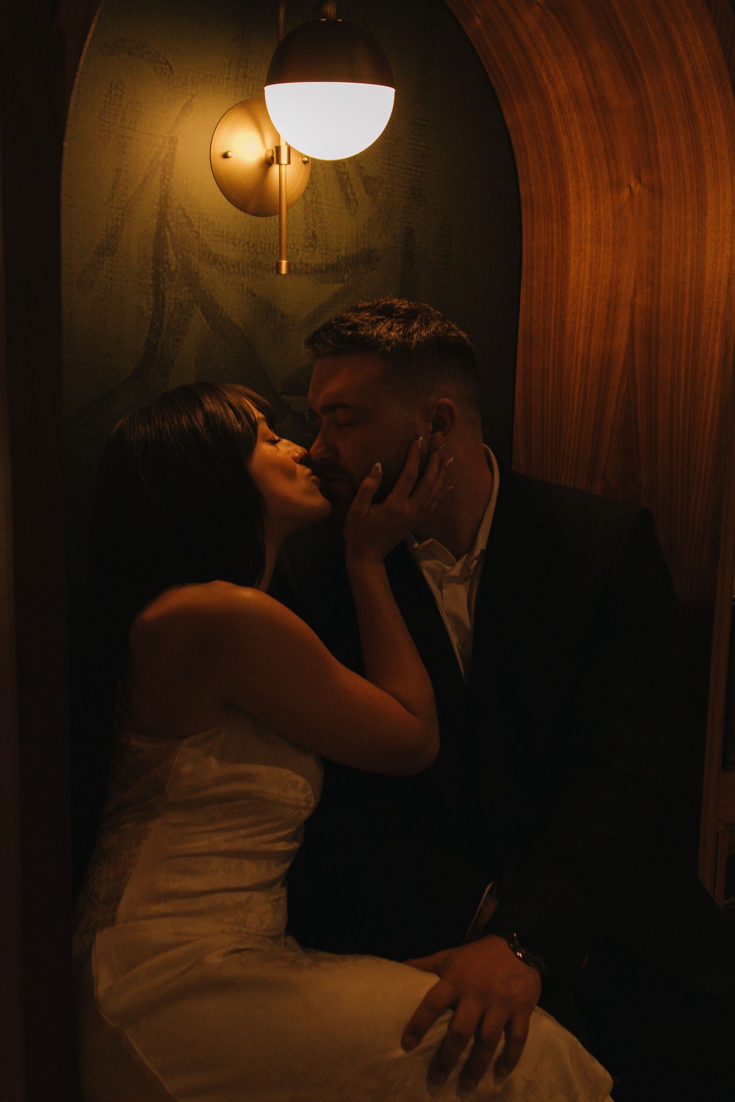 A couple embraces in a dimly lit room with warm lighting.