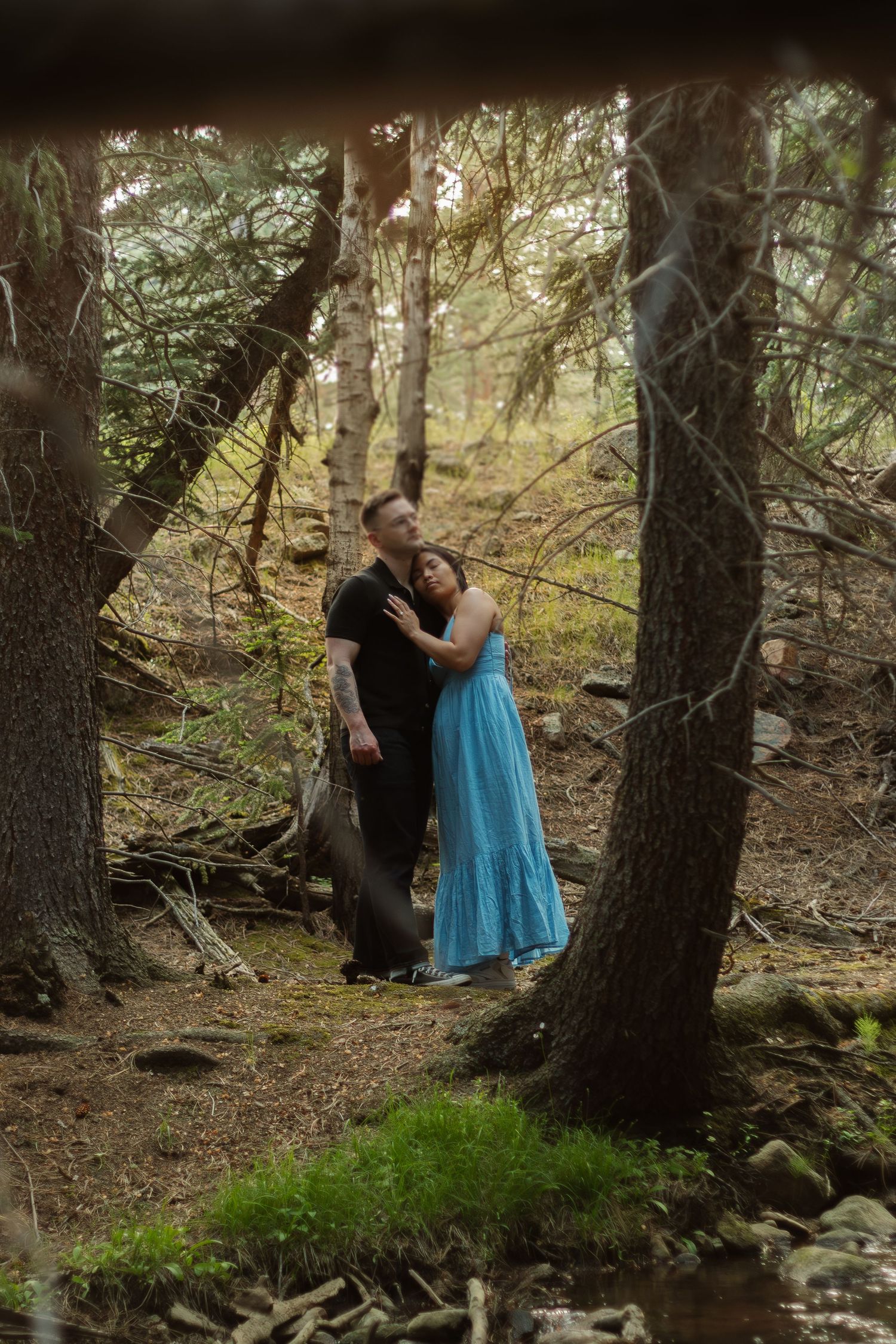 A romantic woodland scene with golden sunlight filtering through trees as a couple embraces.