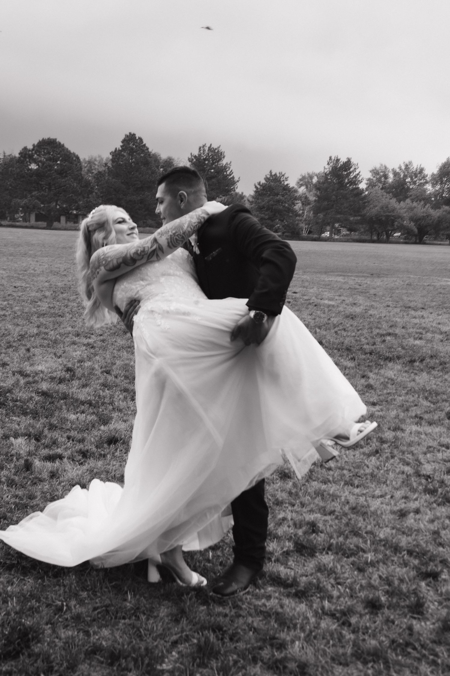 A black and white photo of a romantic wedding dance dip in an open field.