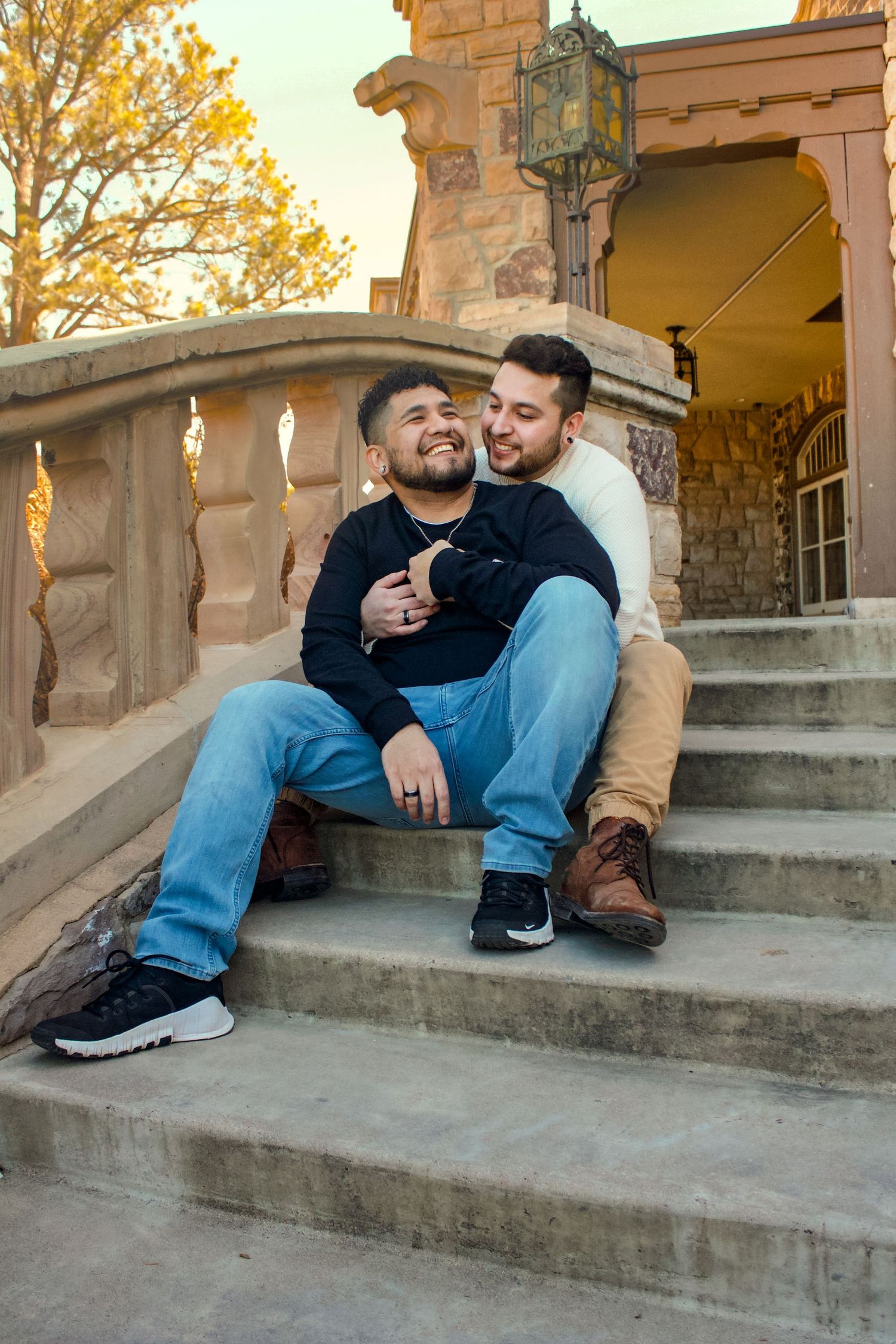 Two people sharing a tender moment while sitting on stone steps at sunset.