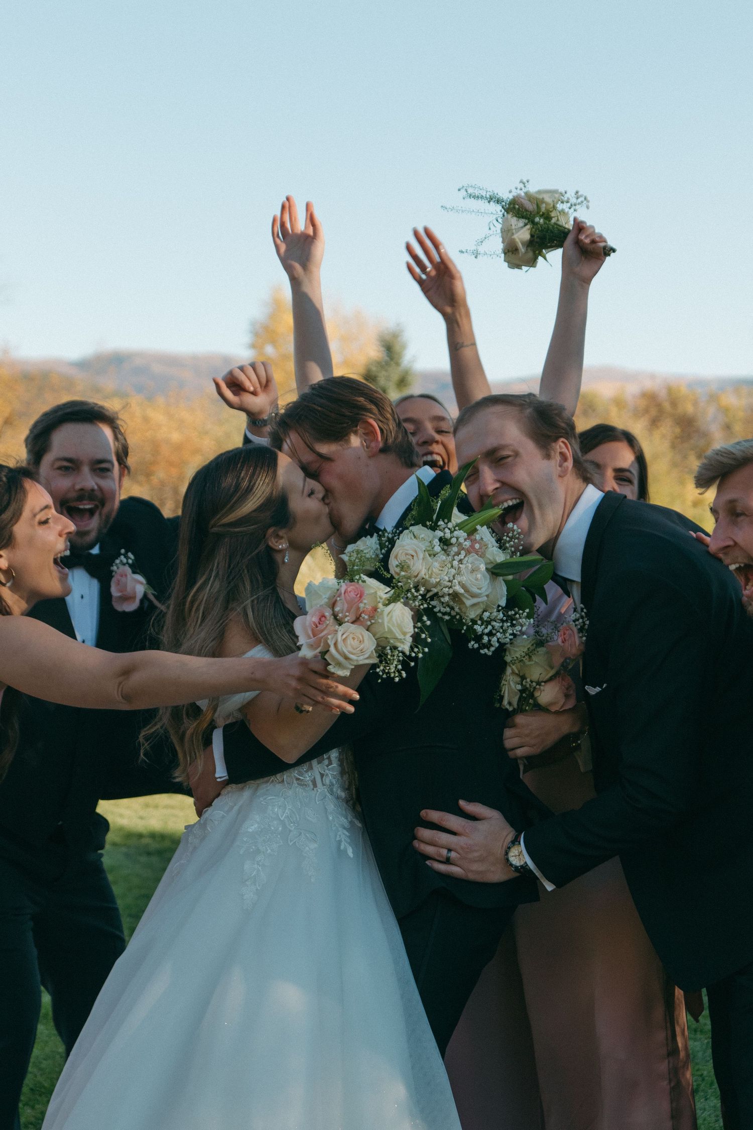 Wedding party celebrates outdoors with raised arms and joyful expressions in a series of candid group photos.