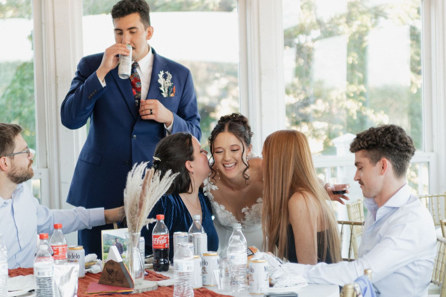 Wedding reception guests enjoying a meal at tables decorated with white linens.