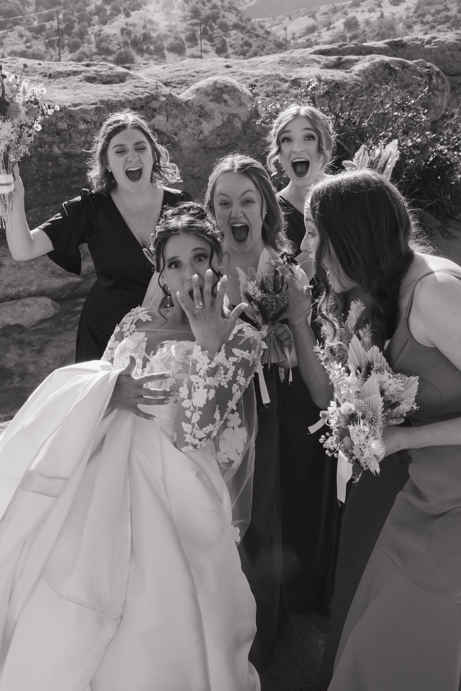 Wedding party poses playfully for black and white group photos outdoors.