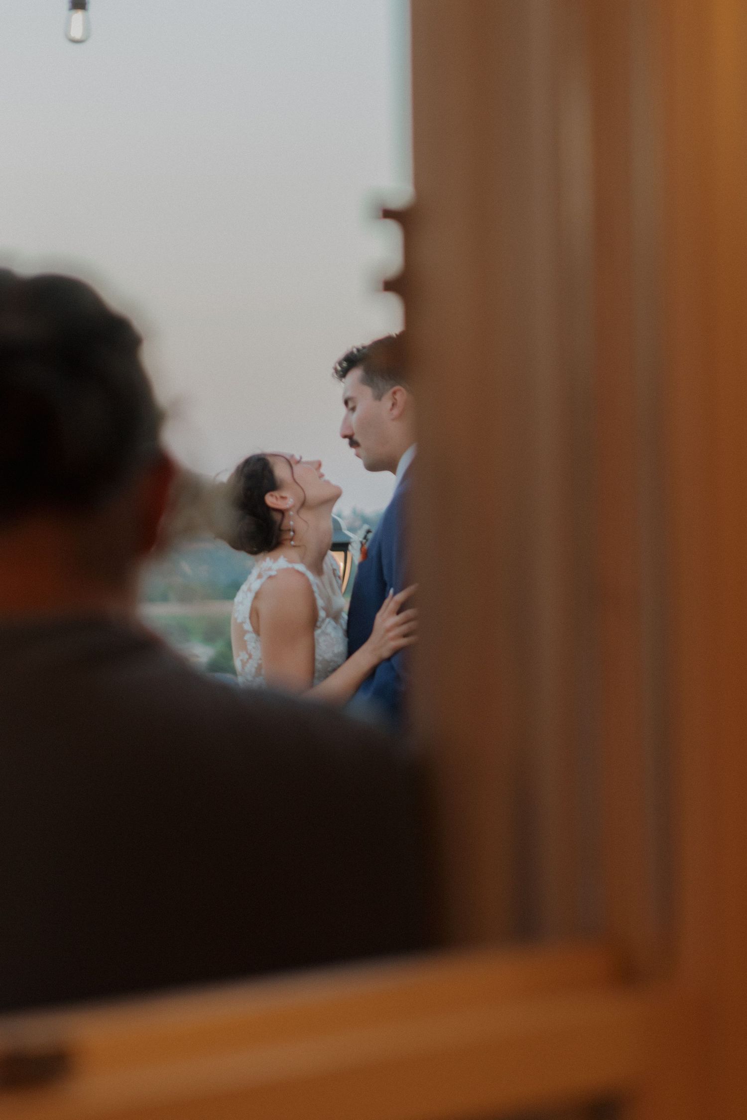 A tender moment captured through a doorway frame at a wedding venue.