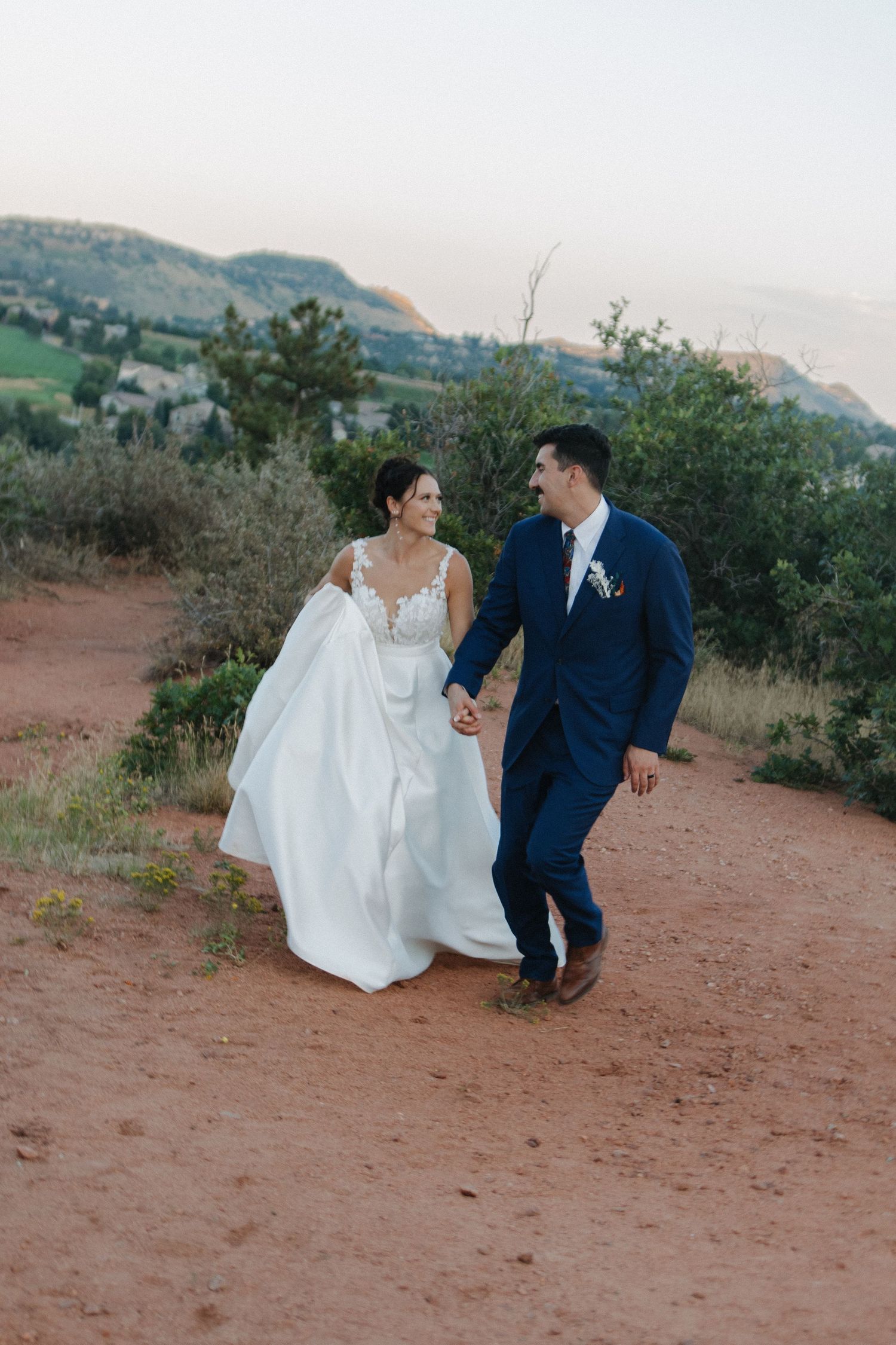 A couple walking together on a scenic mountain trail during a wedding photoshoot.