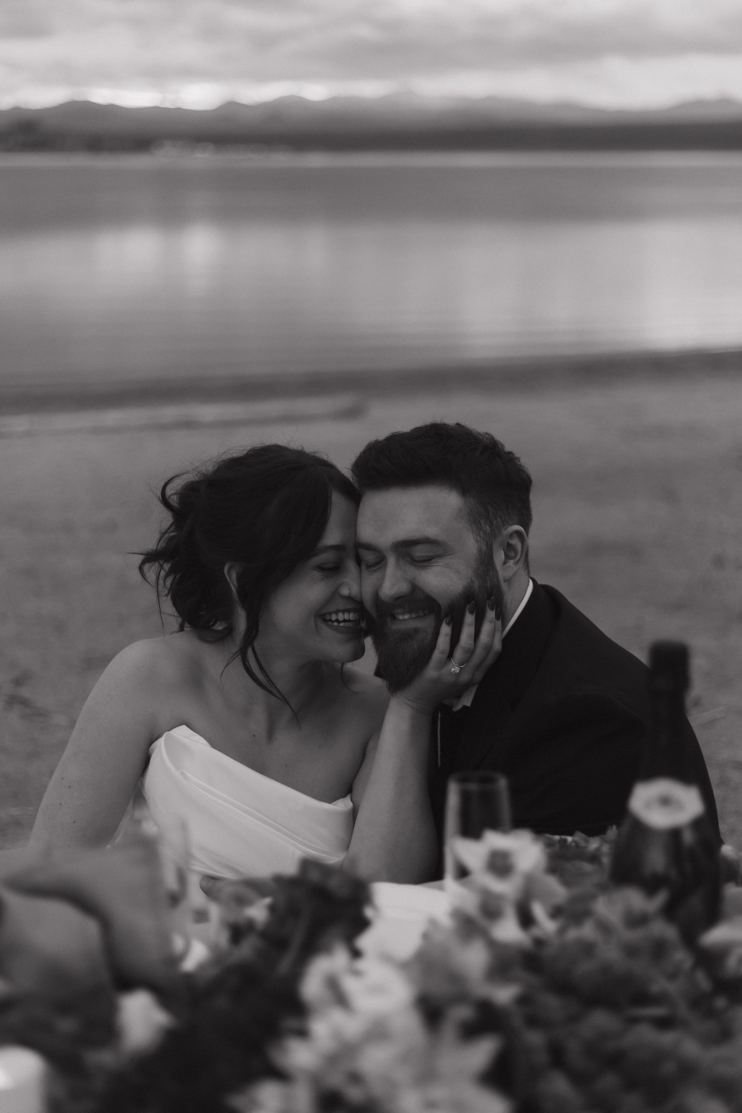 Intimate moment shared against scenic mountain lake backdrop with floral decor.
