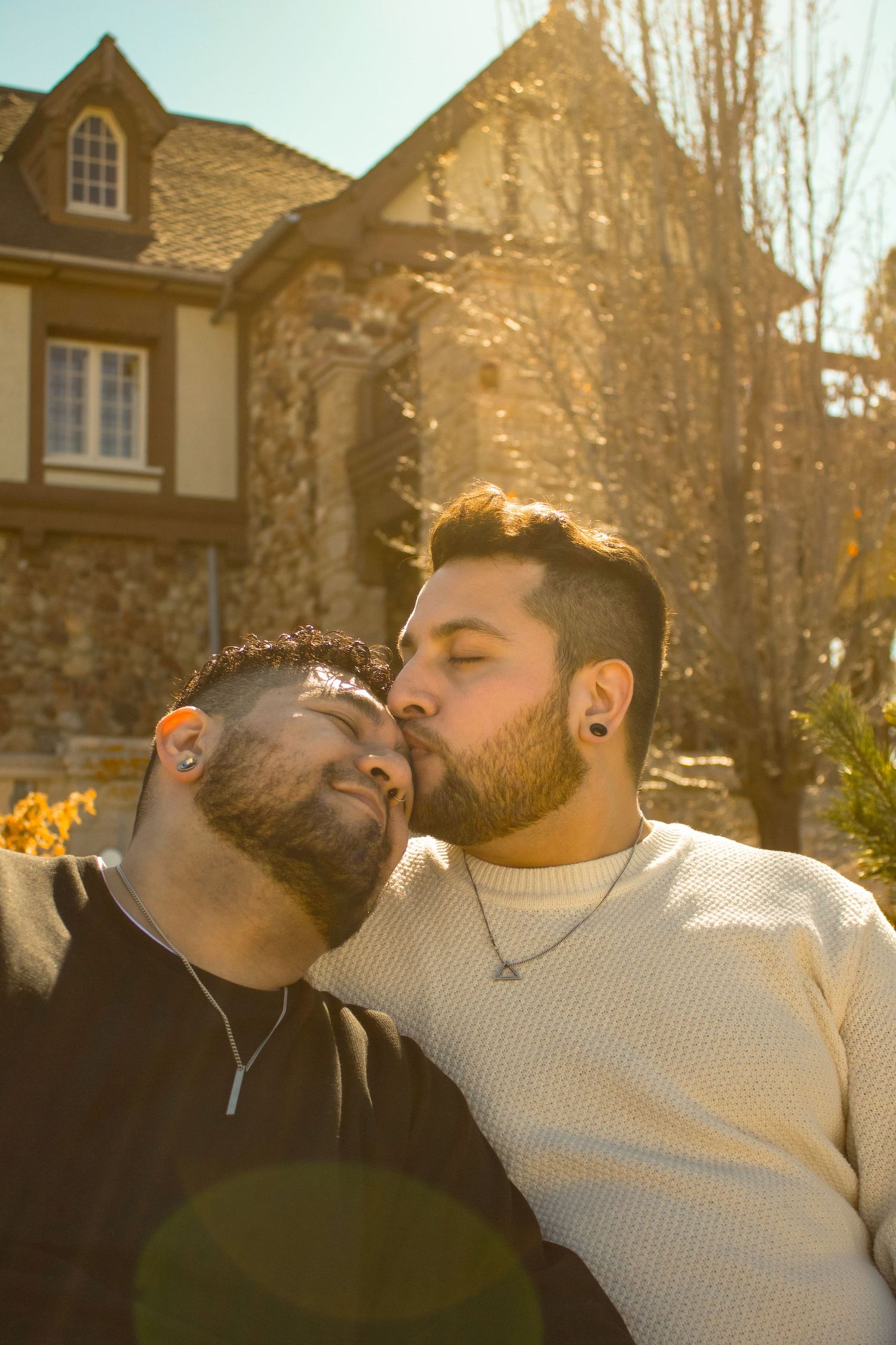 A tender moment captured between two people in front of a stone mansion on a sunny autumn day.