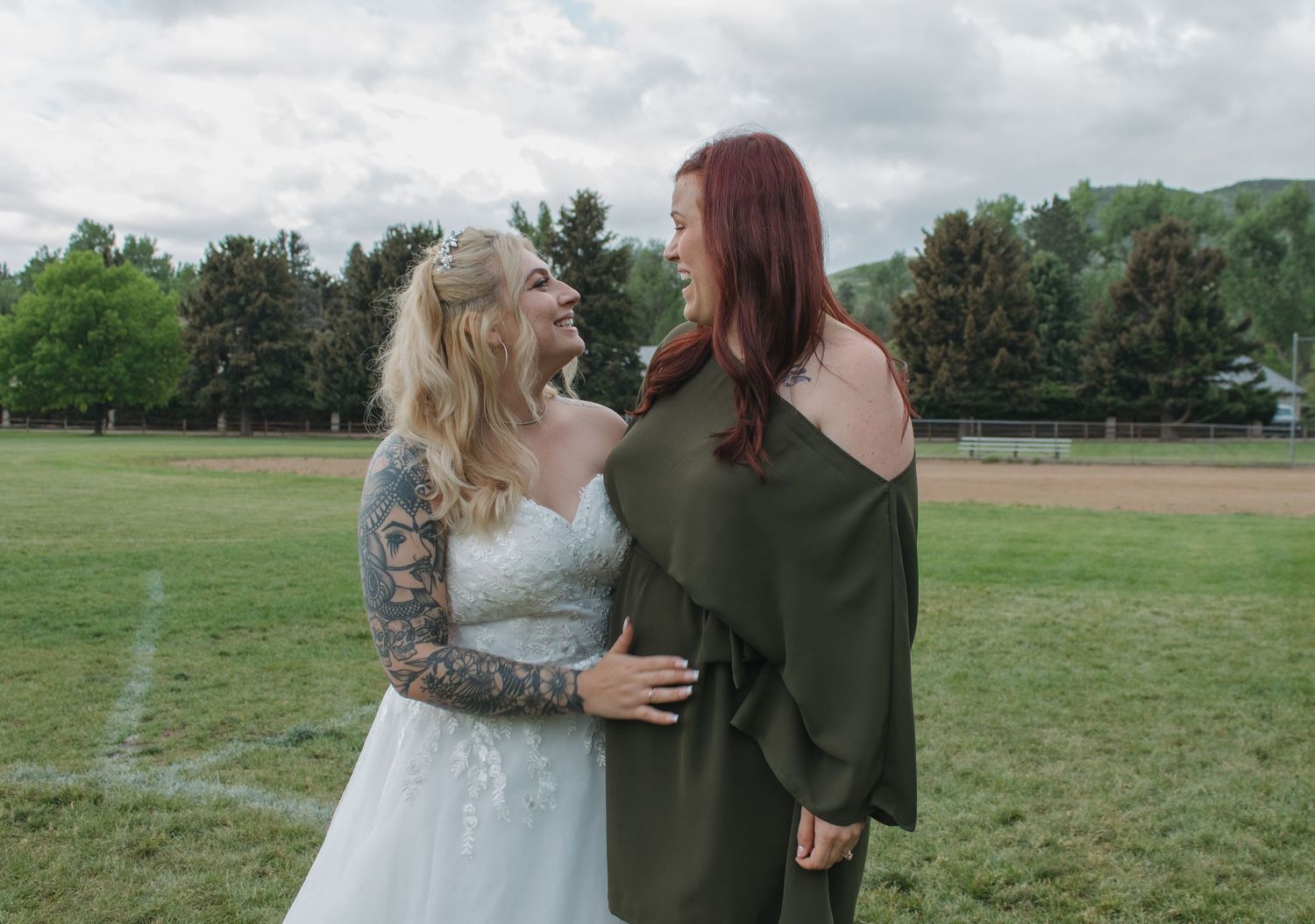 People embrace during an outdoor photo session in a green field.
