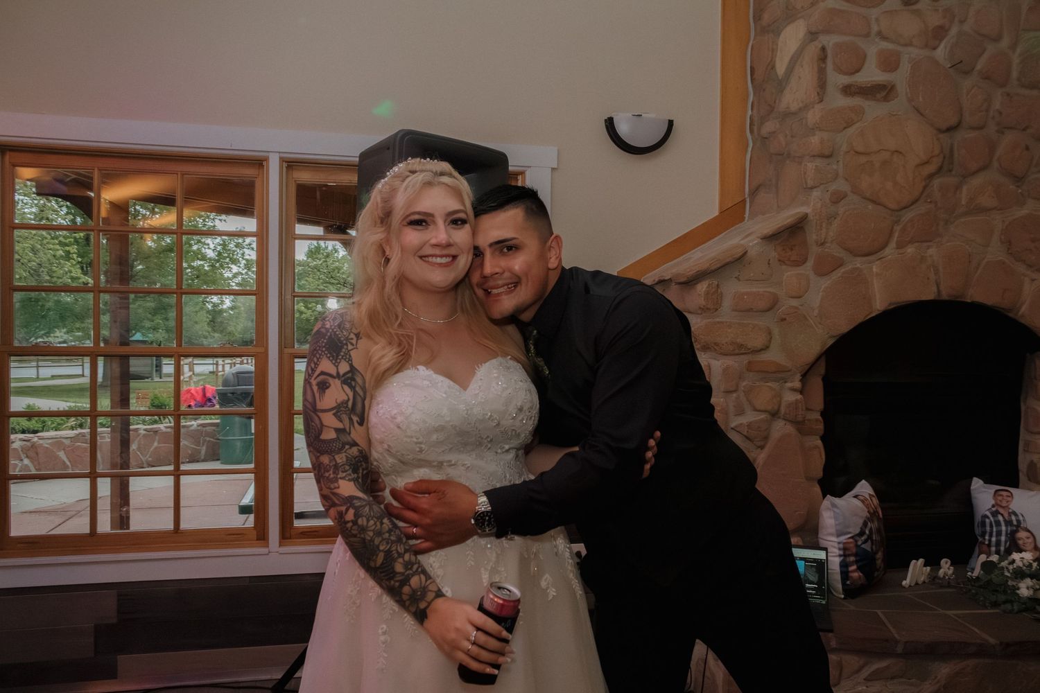Newlyweds sharing an intimate moment against stone fireplace backdrop at their reception.
