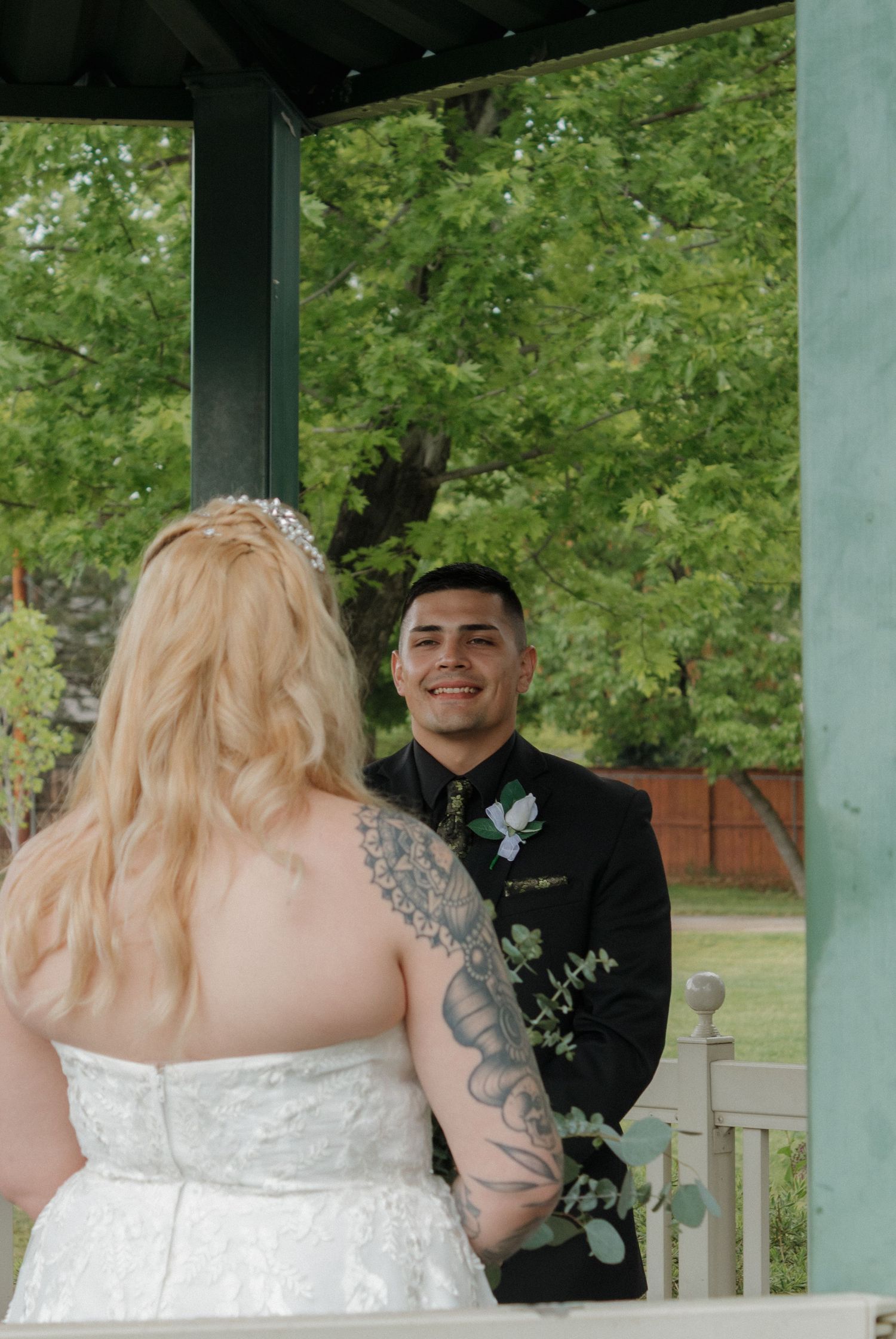 A couple shares a joyful moment during their wedding ceremony on a gazebo.