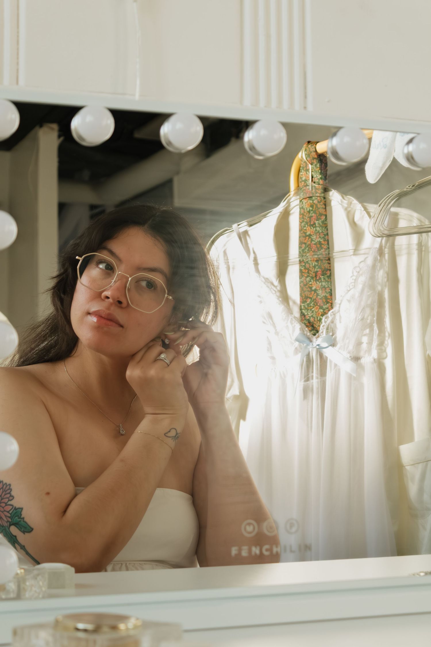 Wedding preparation scene with white dress hanging and vanity mirror lights.