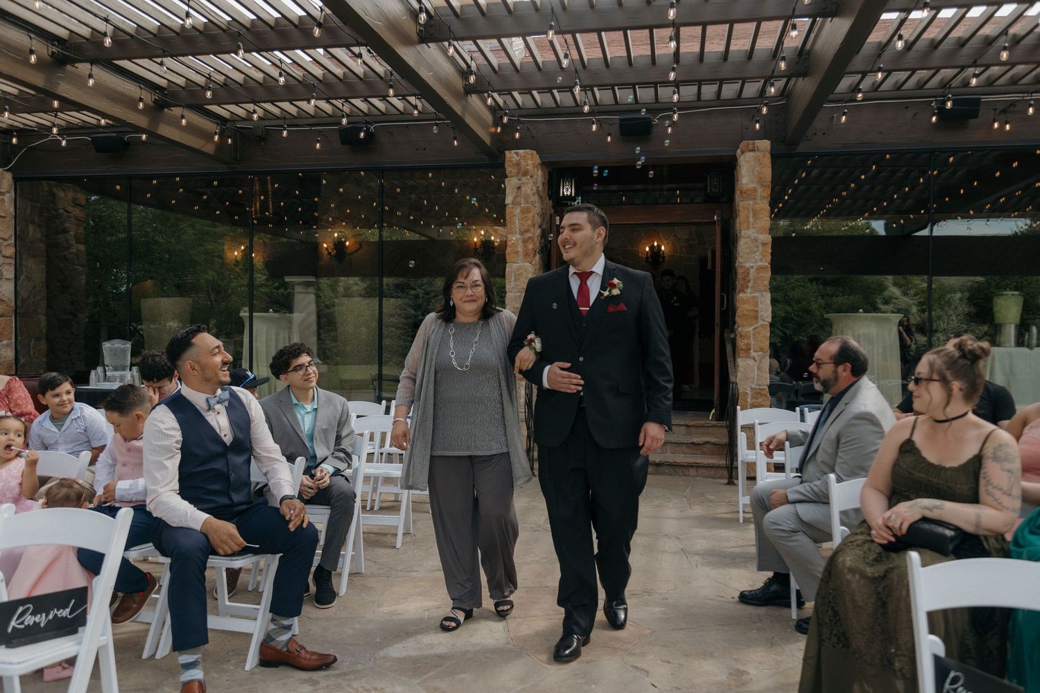 Groom walks down the aisle with his mother at a beautiful wedding ceremony venue.
