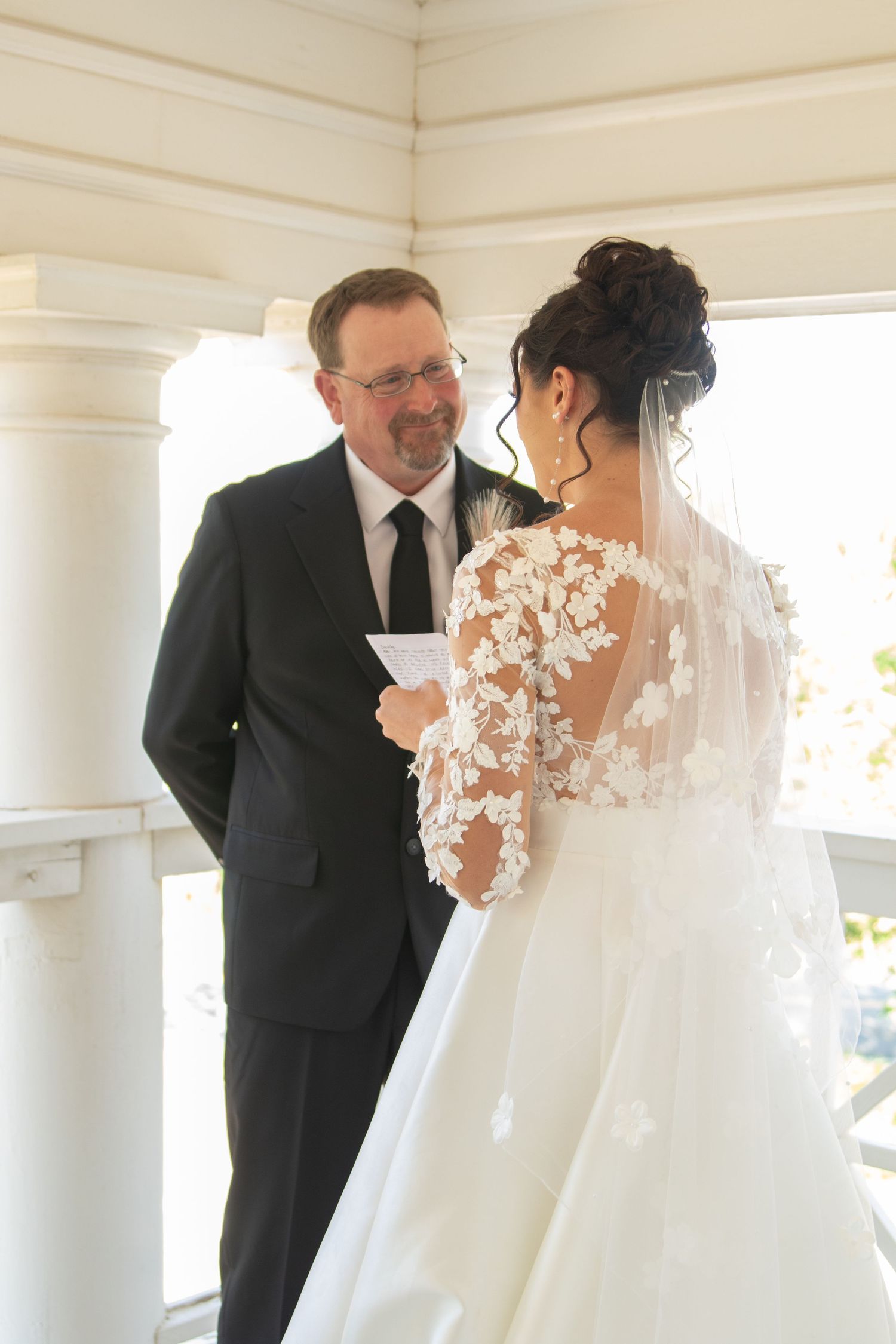 First look moment between couple on a white columned porch with delicate lace detail on wedding dress.