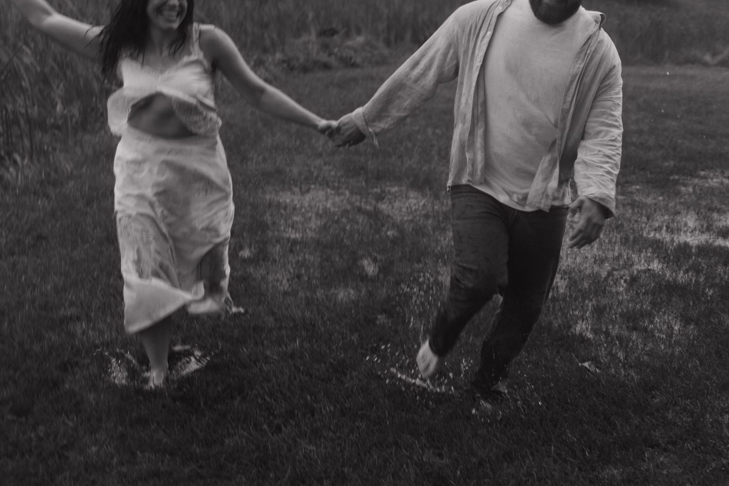 Two people dance together on grass with trees in the background.