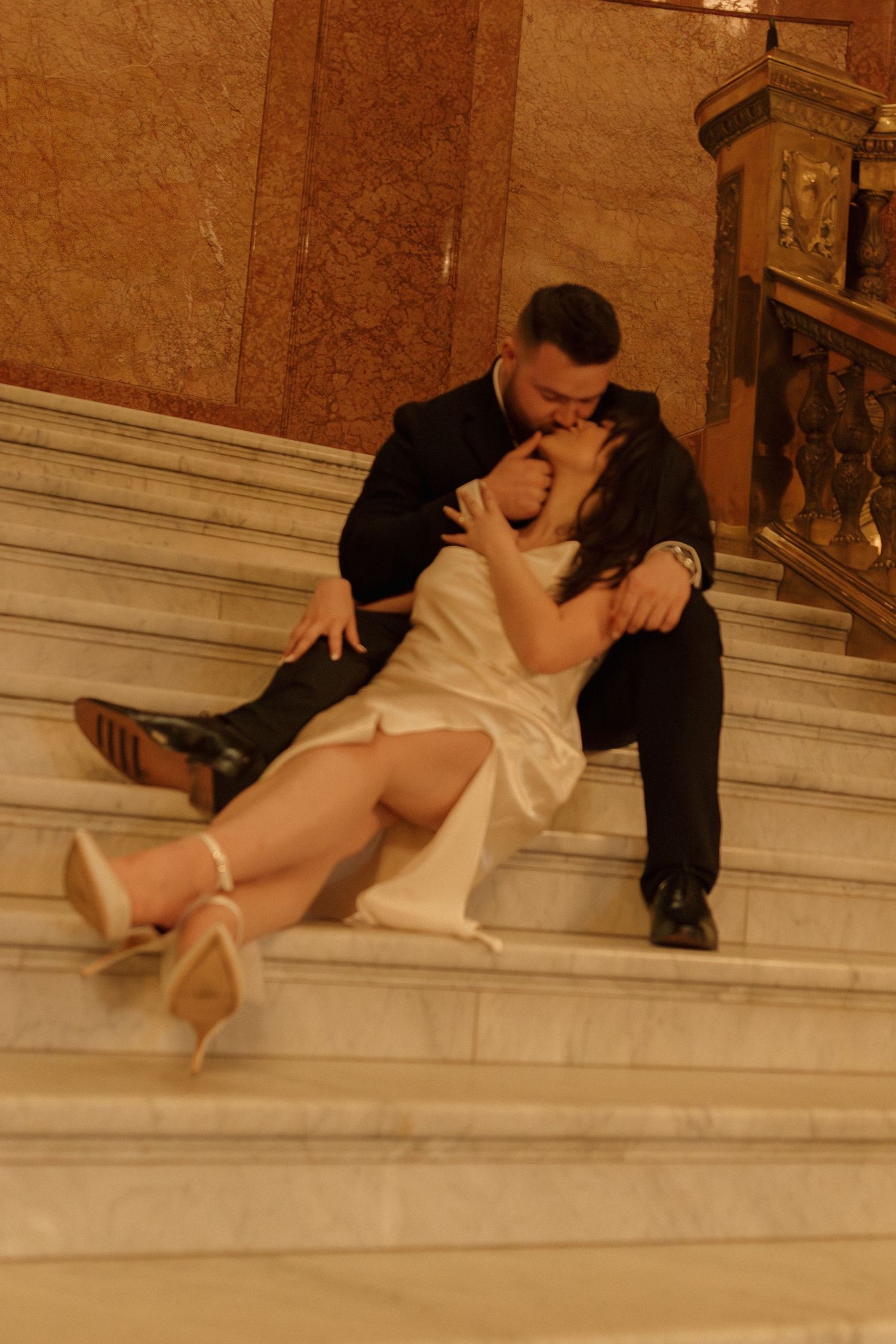 Intimate embrace captured on grand marble steps in an elegant interior setting.
