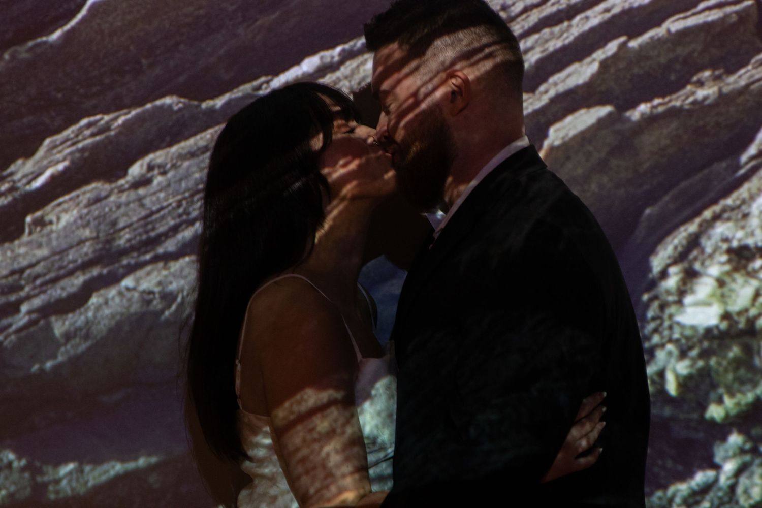Silhouettes of a couple sharing an intimate moment in dim lighting.