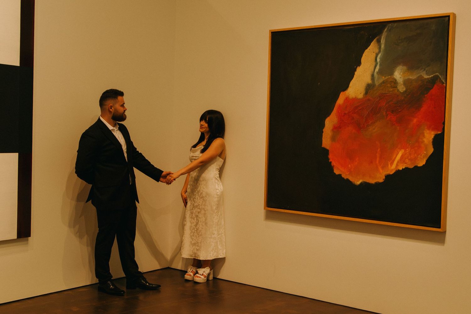 Wide view of an art gallery interior showing multiple framed pieces and visitors viewing the exhibition.