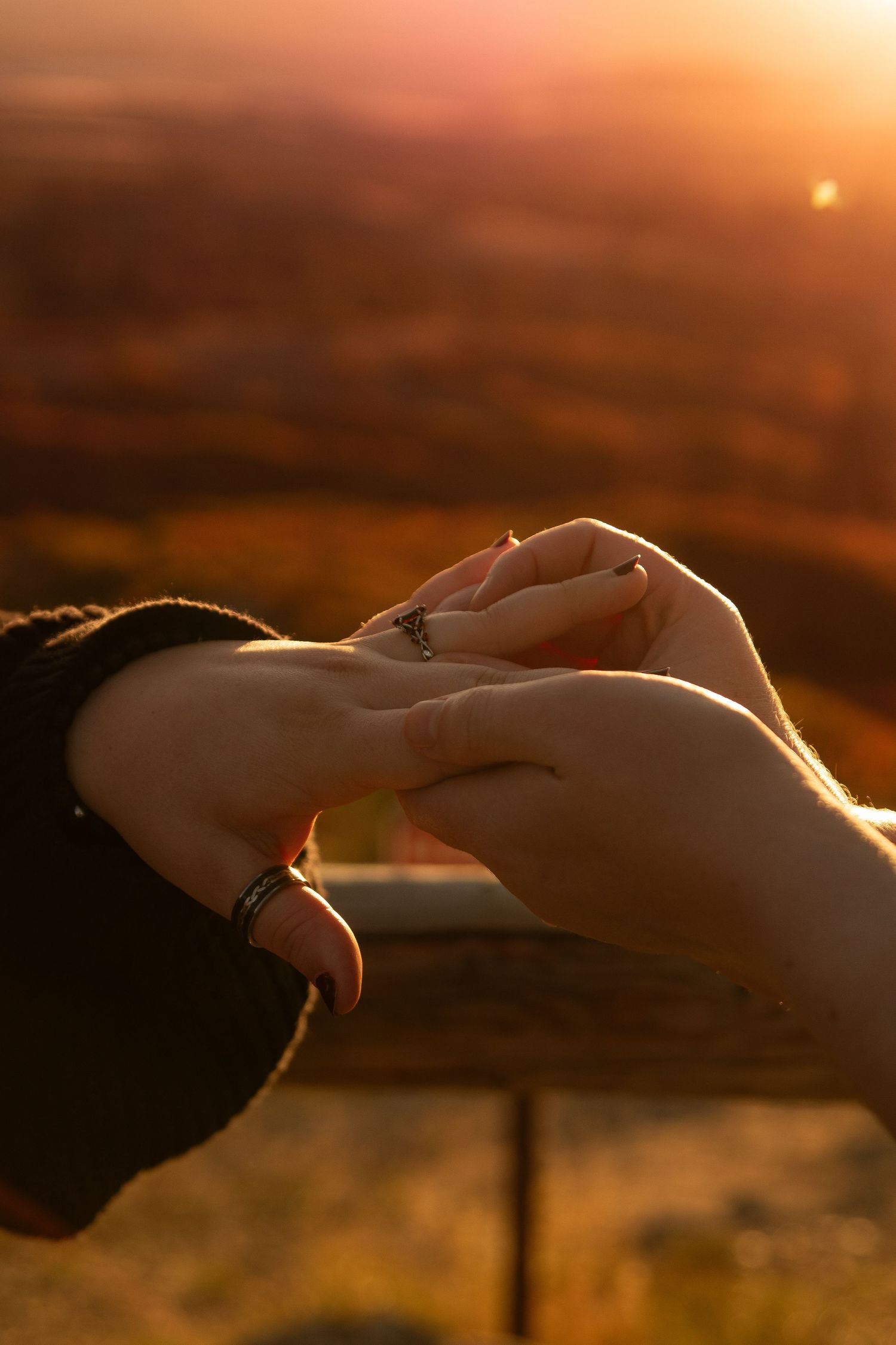 Silhouetted hands reaching towards each other against a warm sunset sky create a romantic atmosphere.