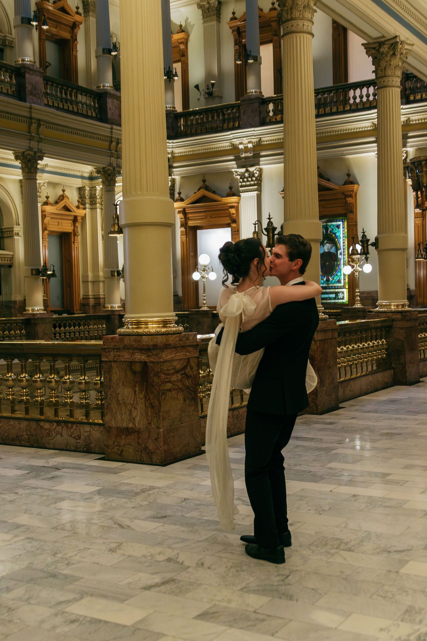 Marble columns line a palatial hallway with ornate architectural details and classical design elements.