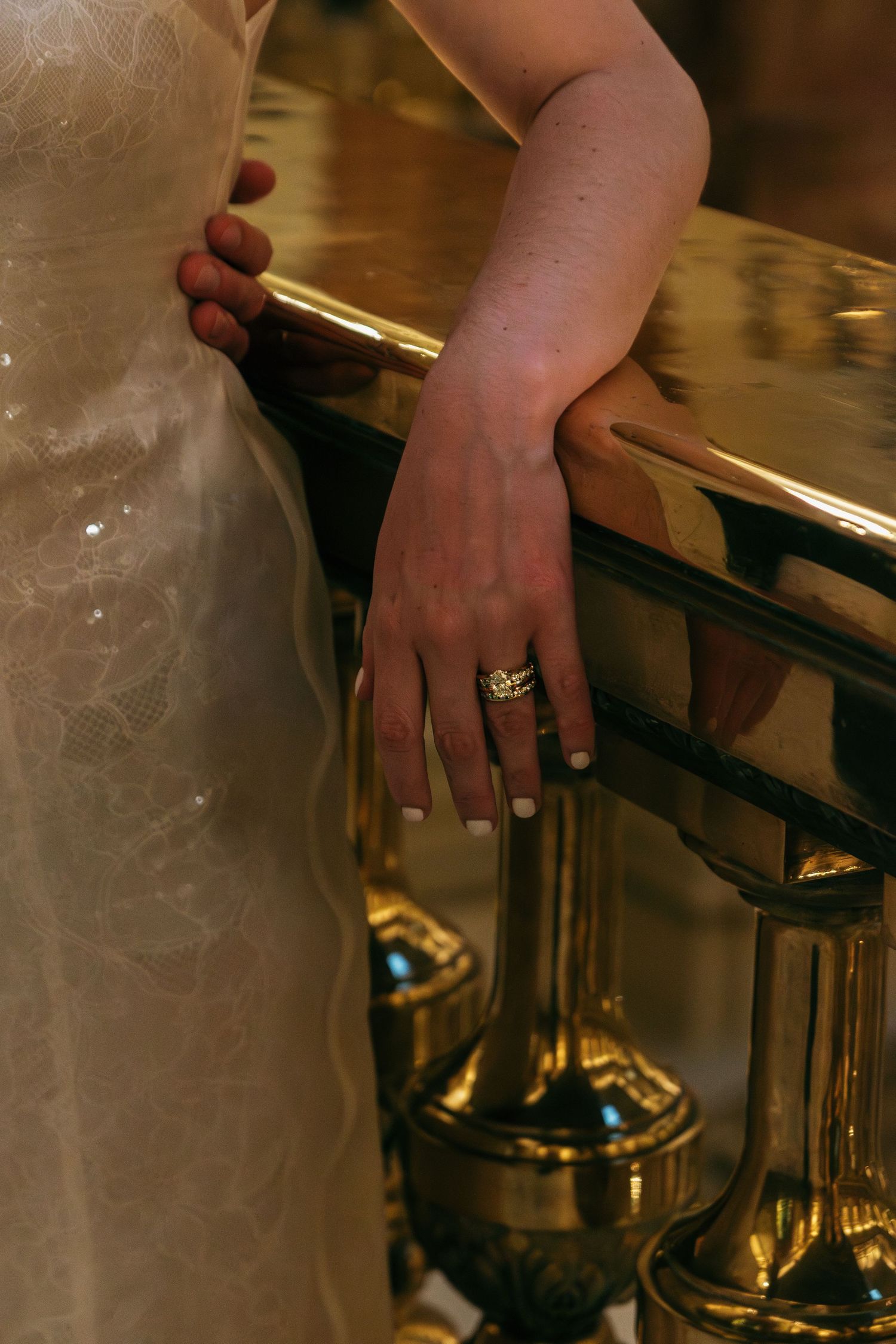 Close-up of hands resting on an elegant gold-trimmed surface with ornate details.