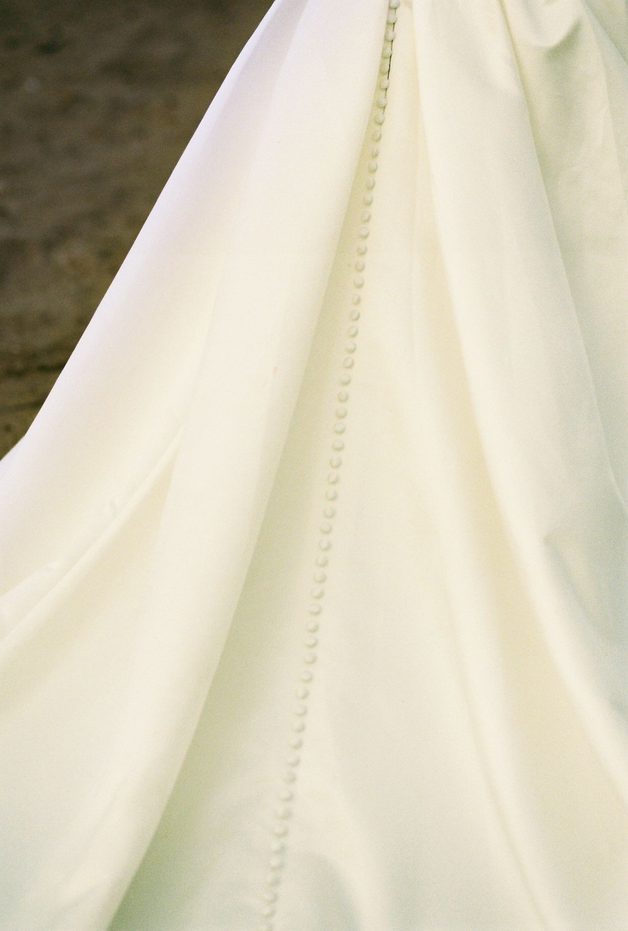 Close-up detail of delicate button closures on an ivory wedding gown.