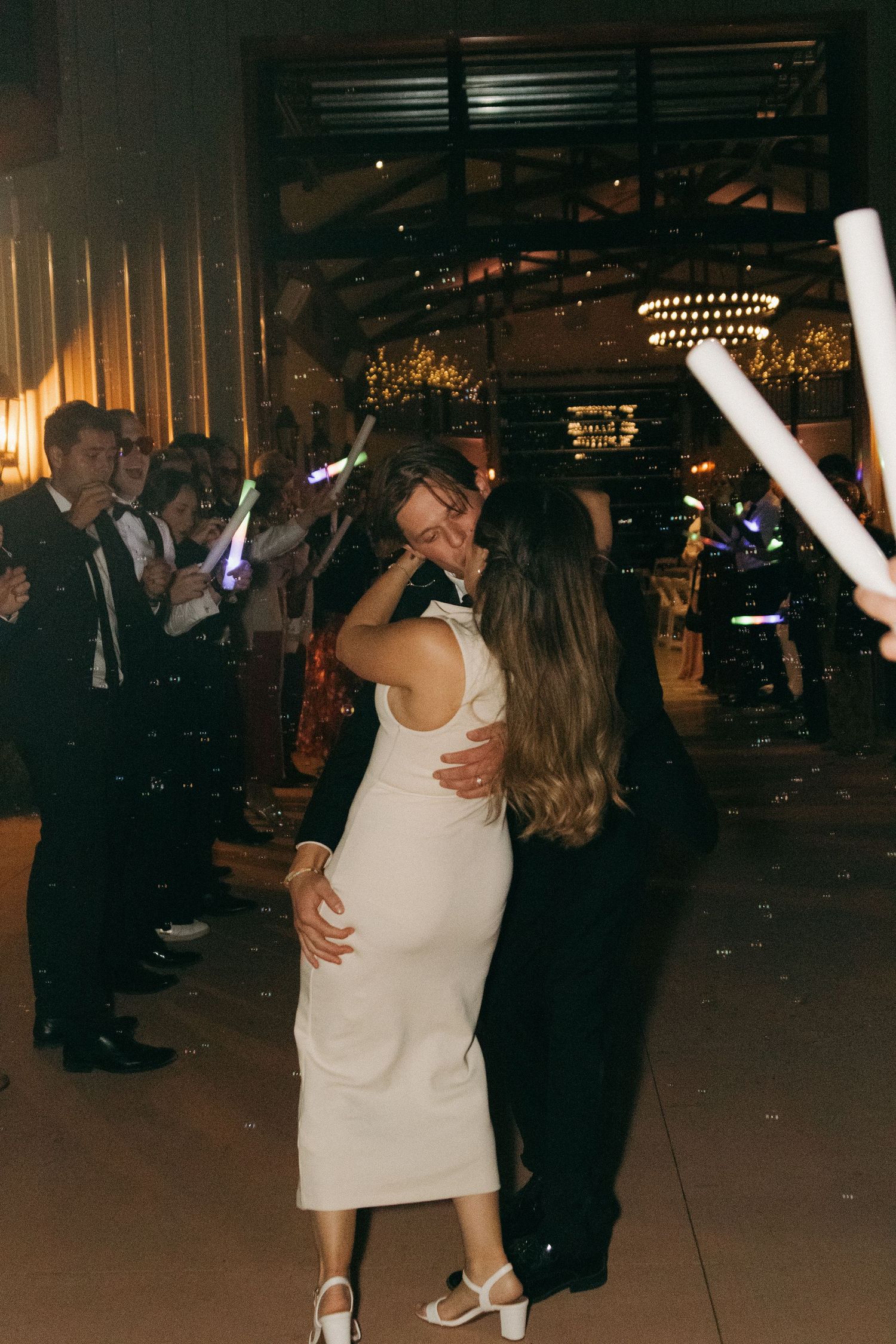 People dancing and celebrating at an evening reception with atmospheric lighting and decorations.