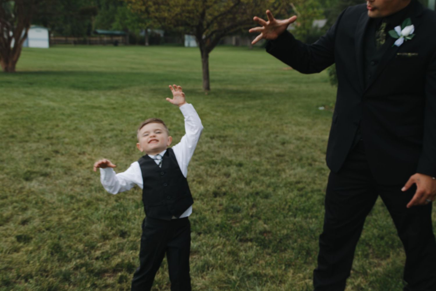 A joyful outdoor wedding scene on a grassy lawn with a bride in a white dress and formal attire.