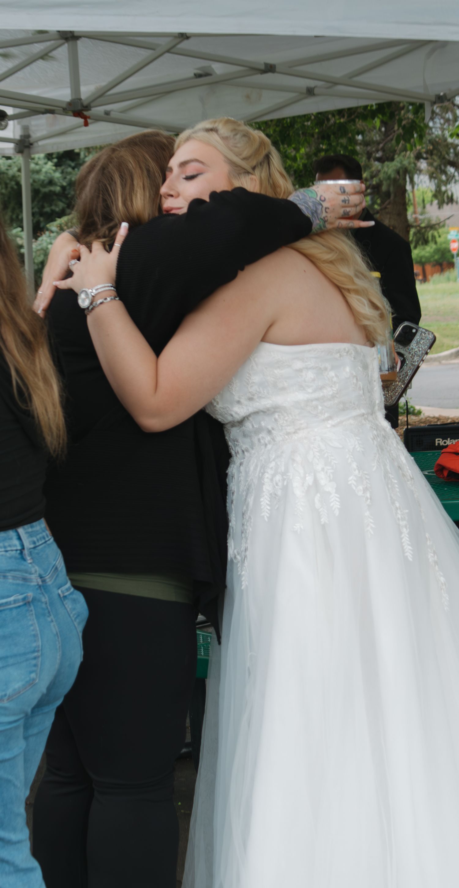 Intimate moments captured as wedding attendees share warm embraces during an outdoor celebration.
