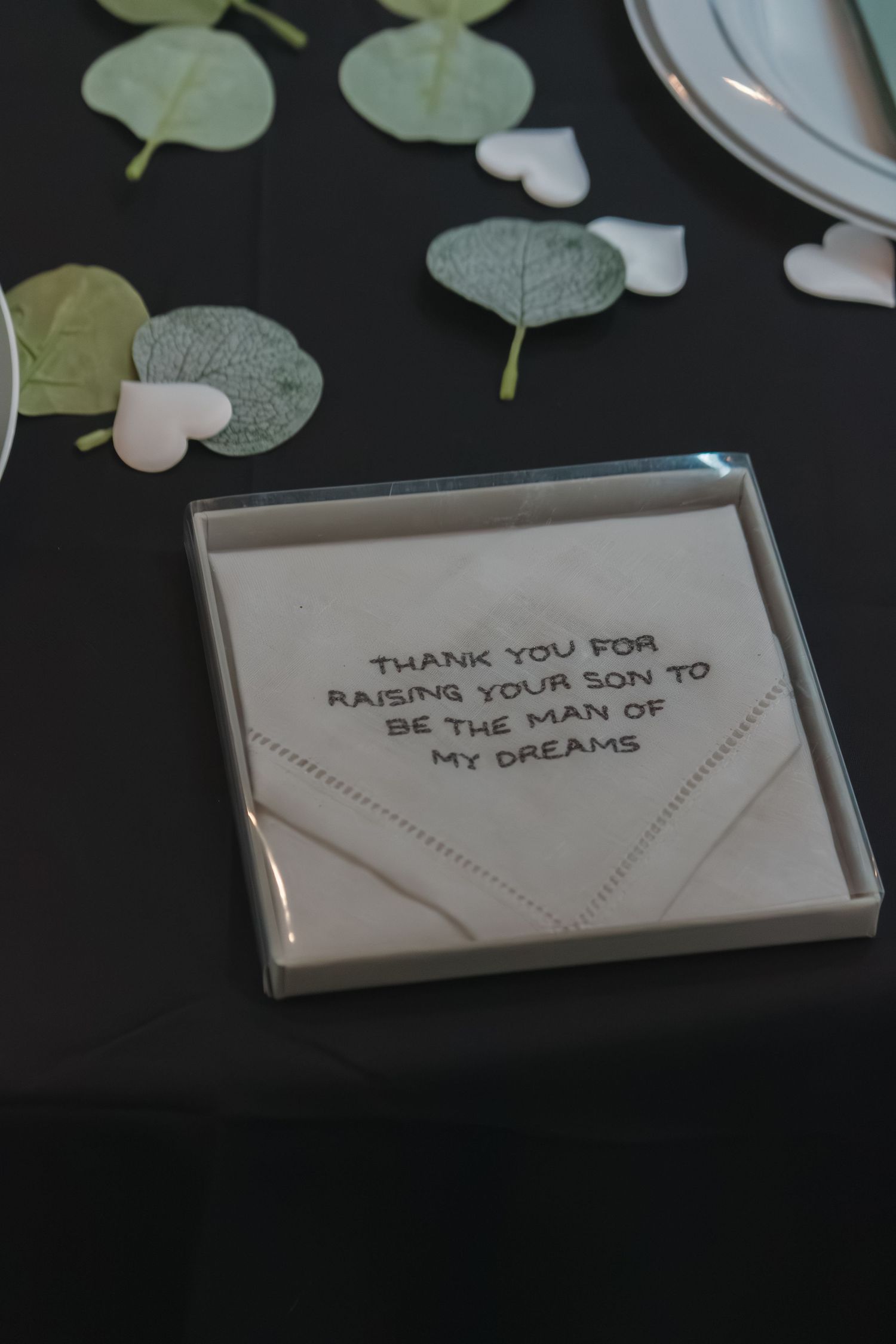 Close-up of thank you note cards with text displayed on dark surface with eucalyptus leaves.