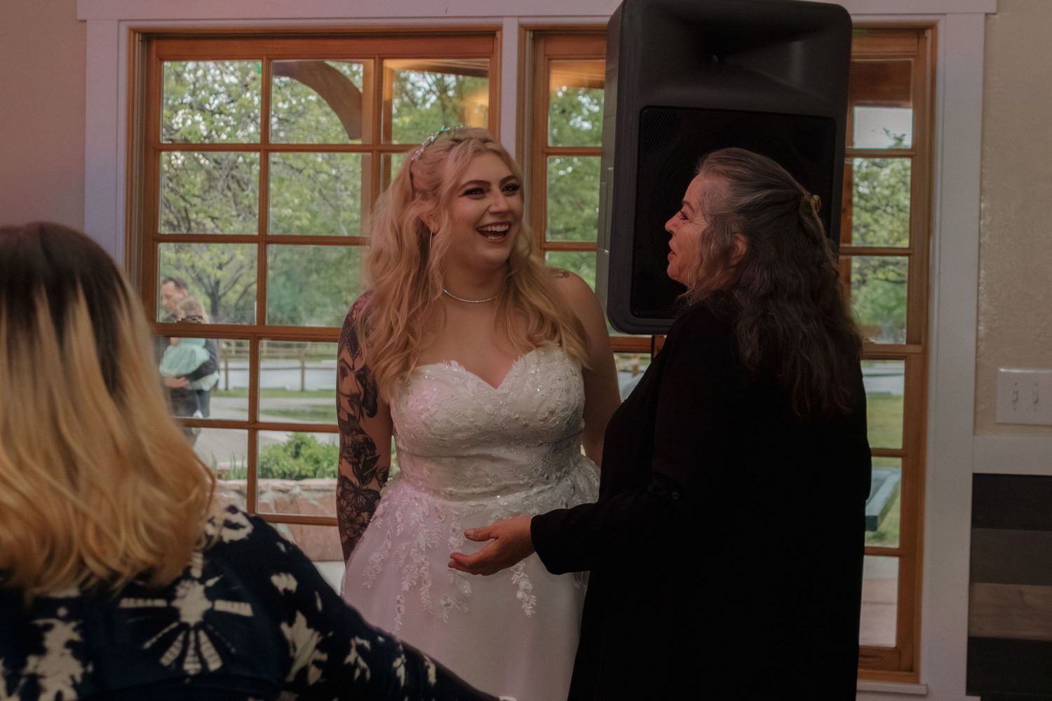 Wedding party celebrating in decorated indoor venue with large windows.