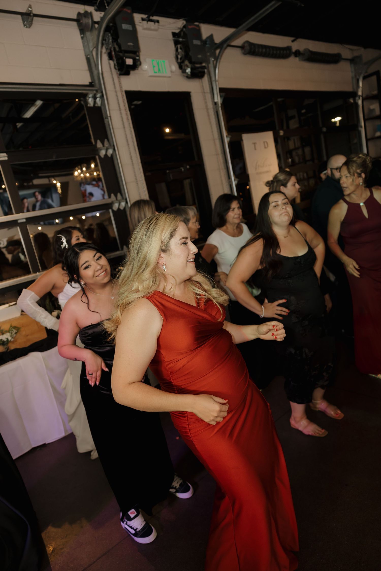Wedding guests in elegant dresses dance joyfully on the reception dance floor.