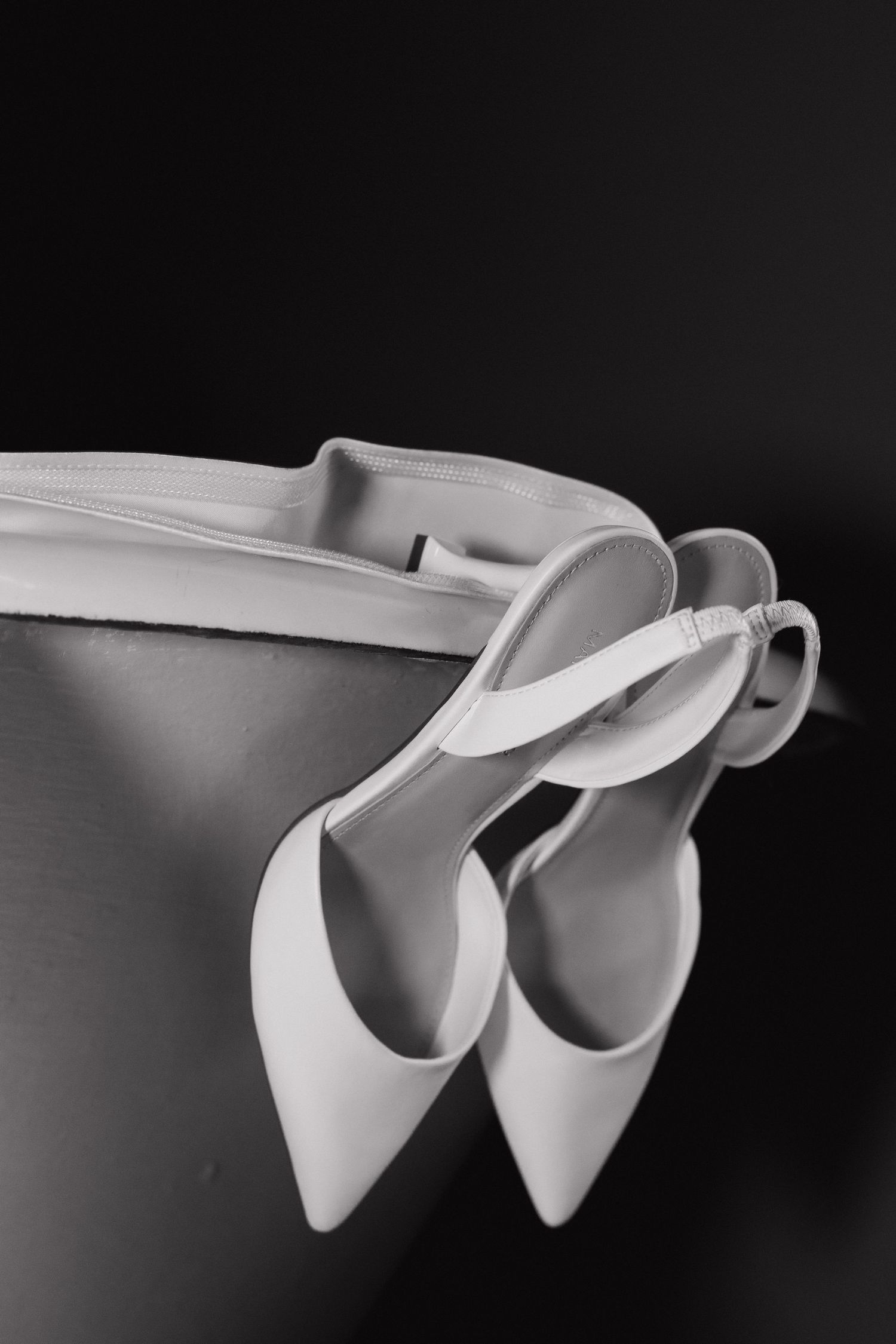White bridal shoes arranged artistically in black and white photography.
