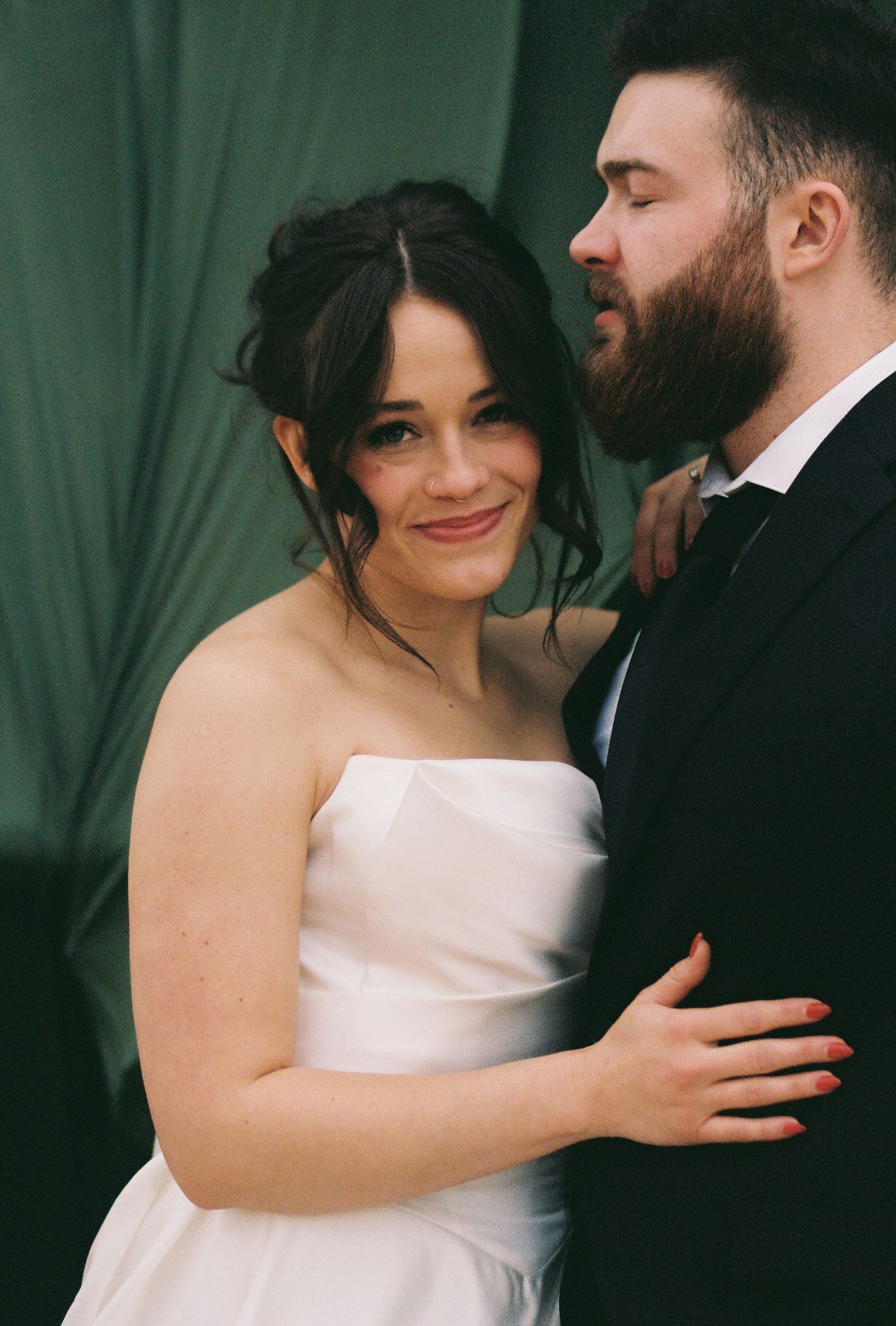 A couple sharing an intimate moment against a dark green backdrop.