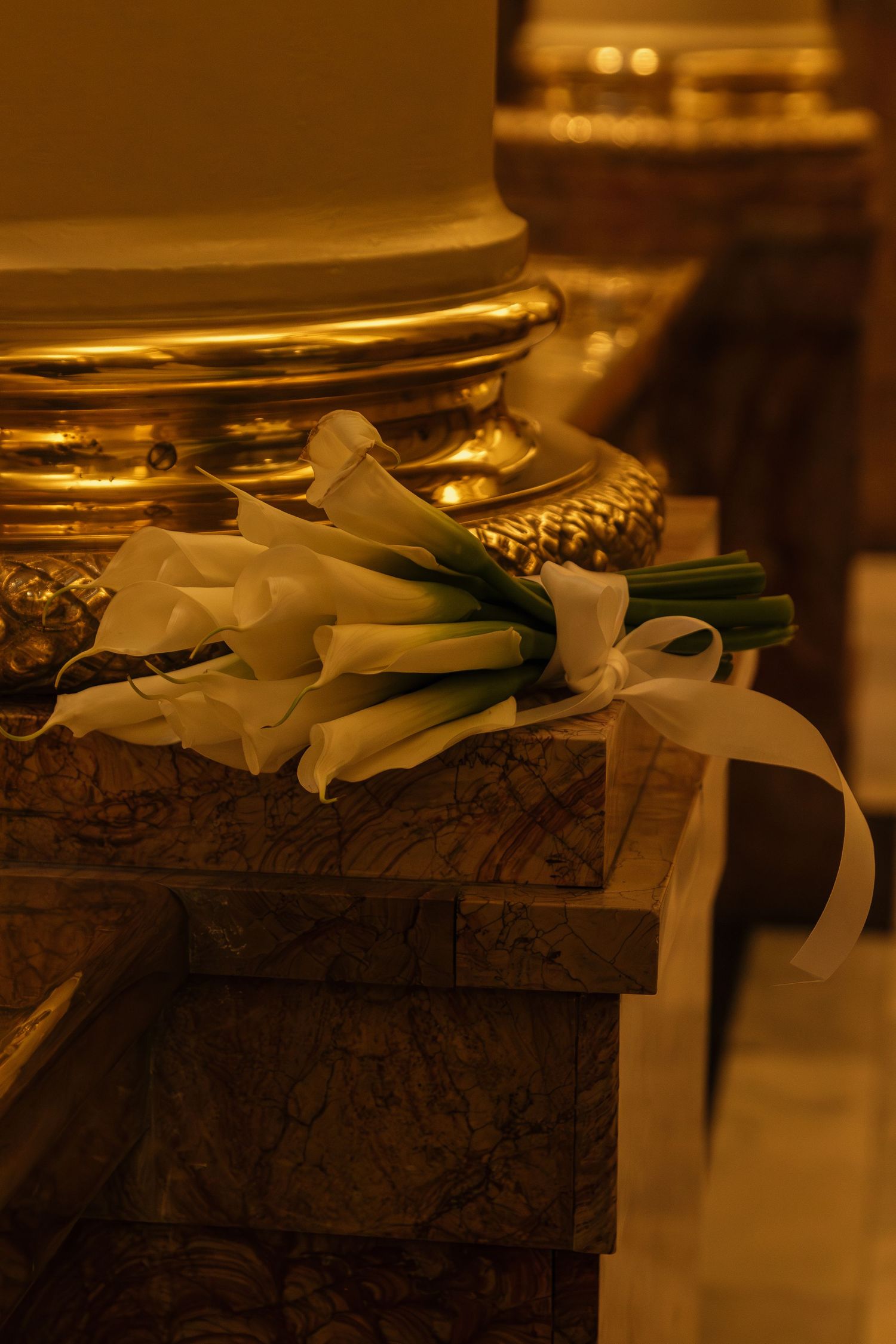 White calla lilies and ribbons decorating an elegant dark chocolate wedding cake.