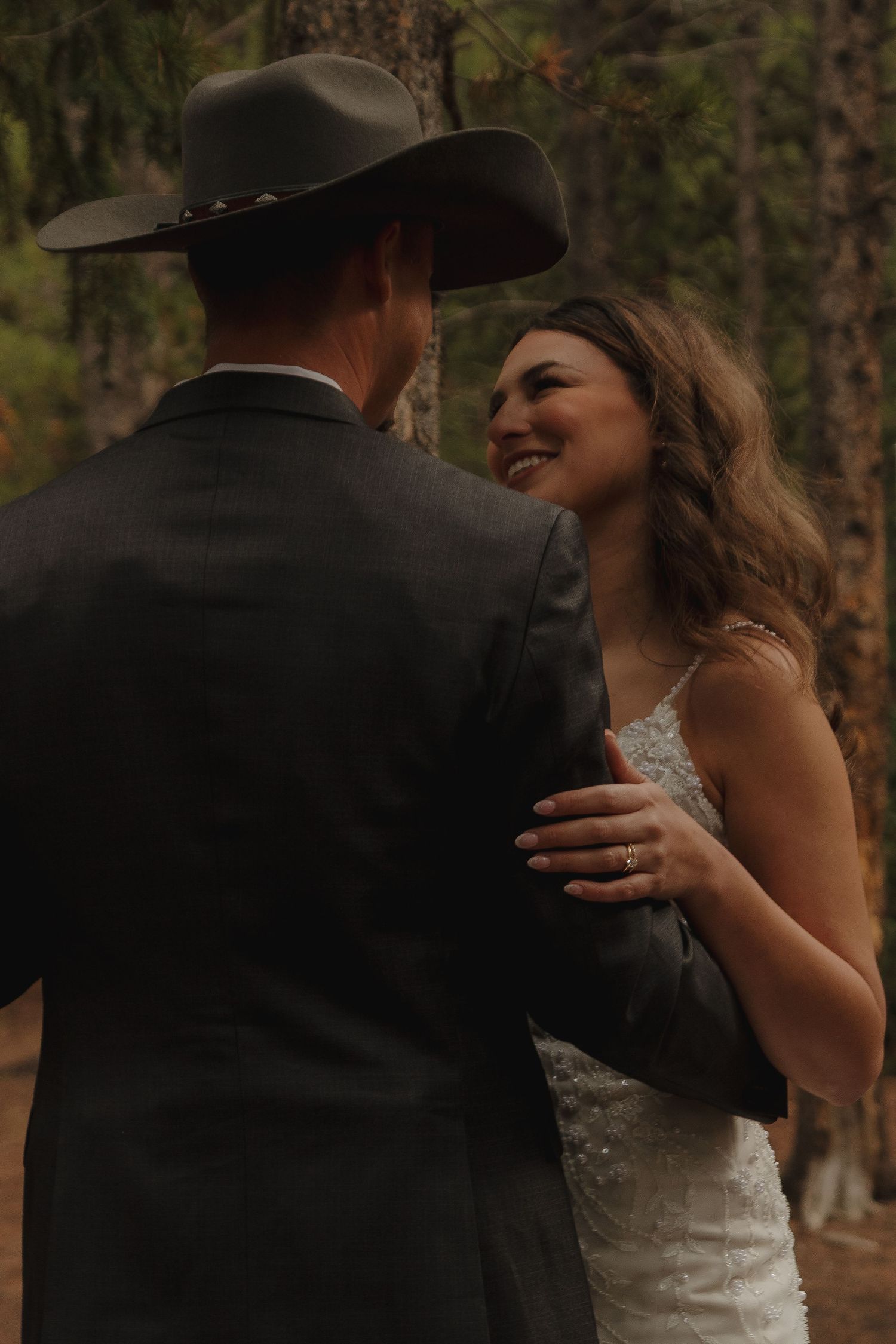 A joyful wedding moment captured between newlyweds in a rustic forest setting.