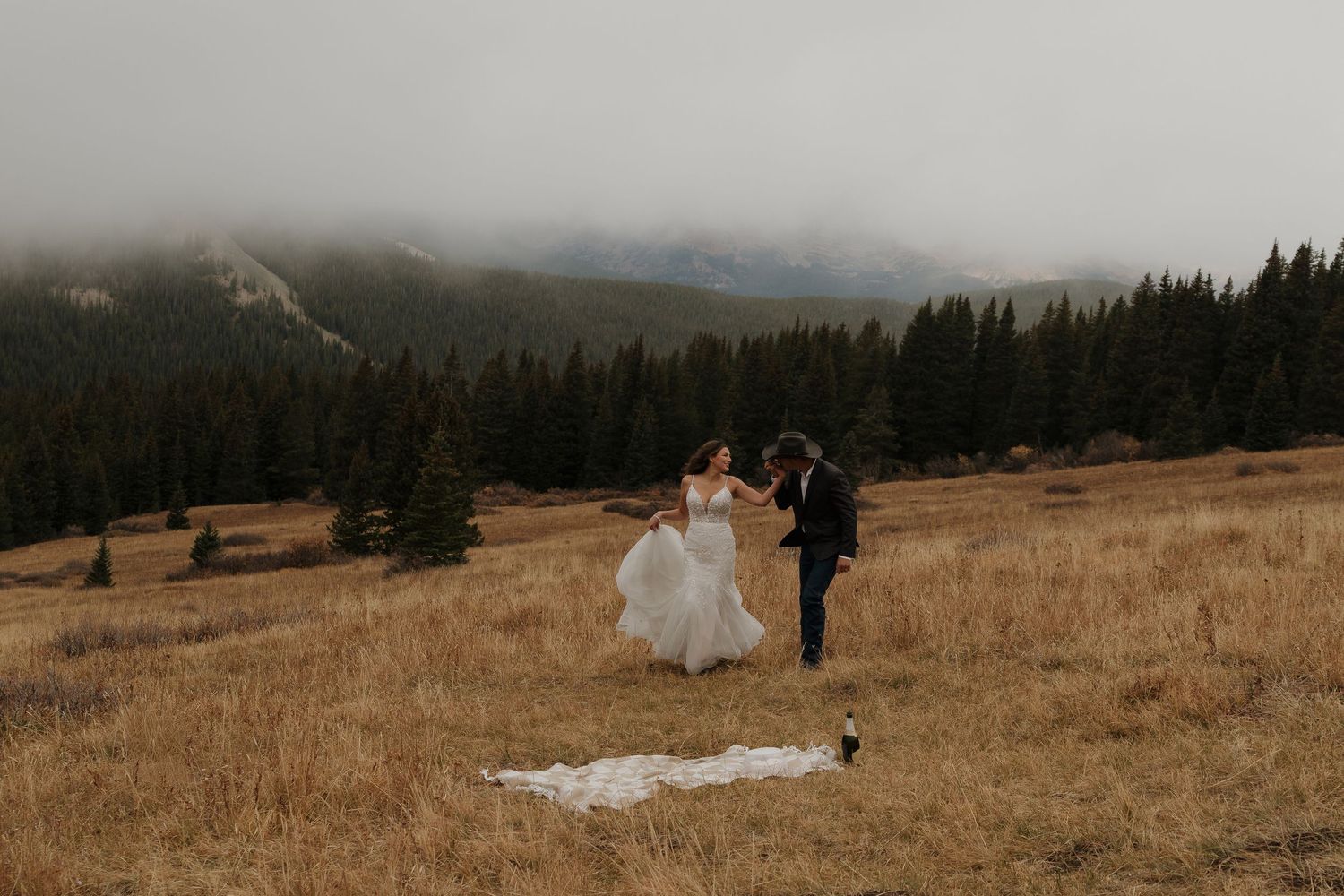 A wide landscape shot of a mountain ceremony site with evergreen forests in the distance.