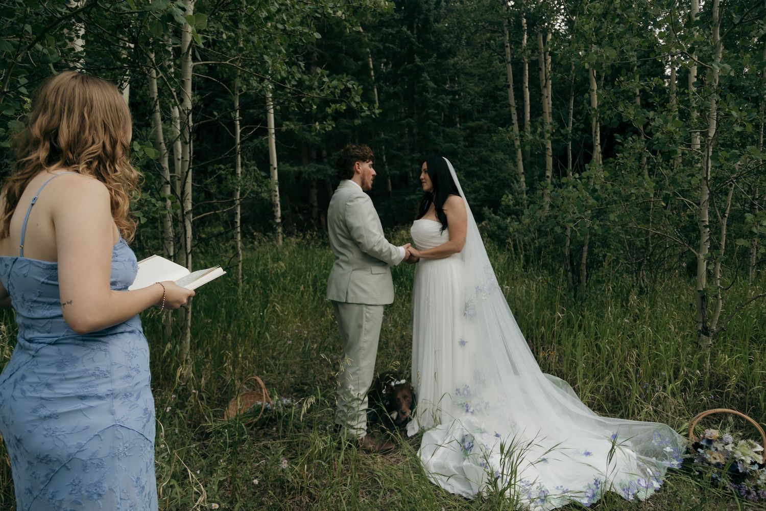 Officiant reads ceremony script as bride and groom exchange vows in an intimate forest elopement.