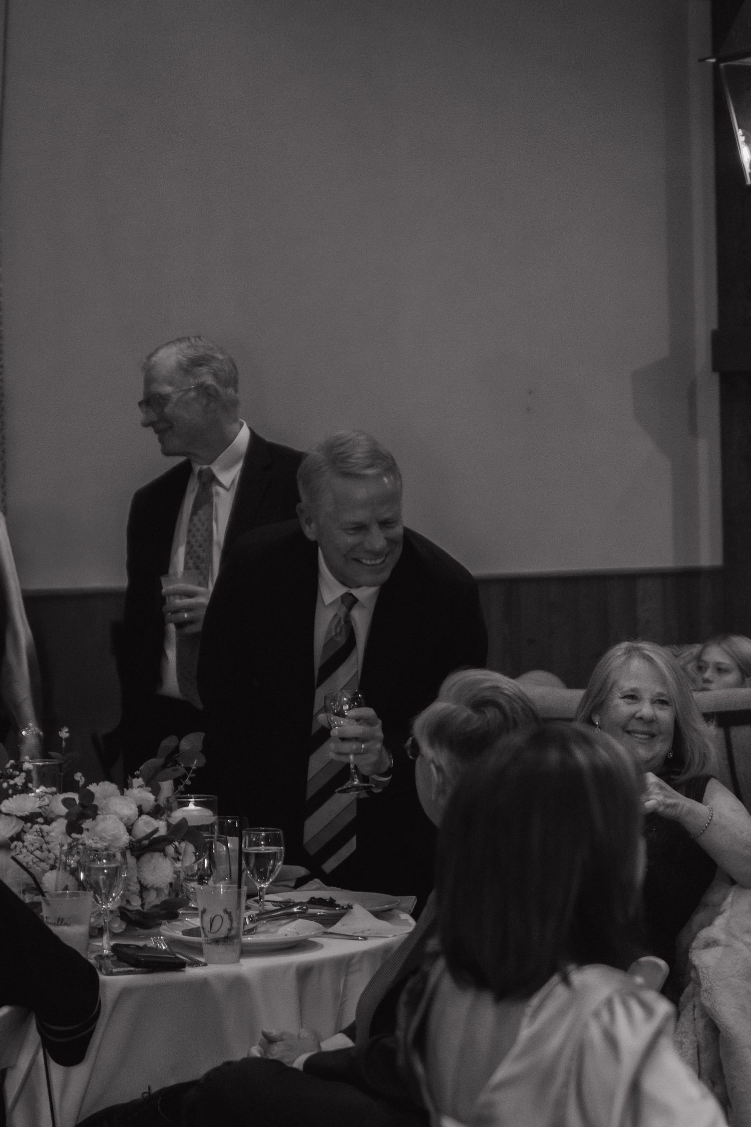 Guests seated at formal dining tables during an indoor celebration event.