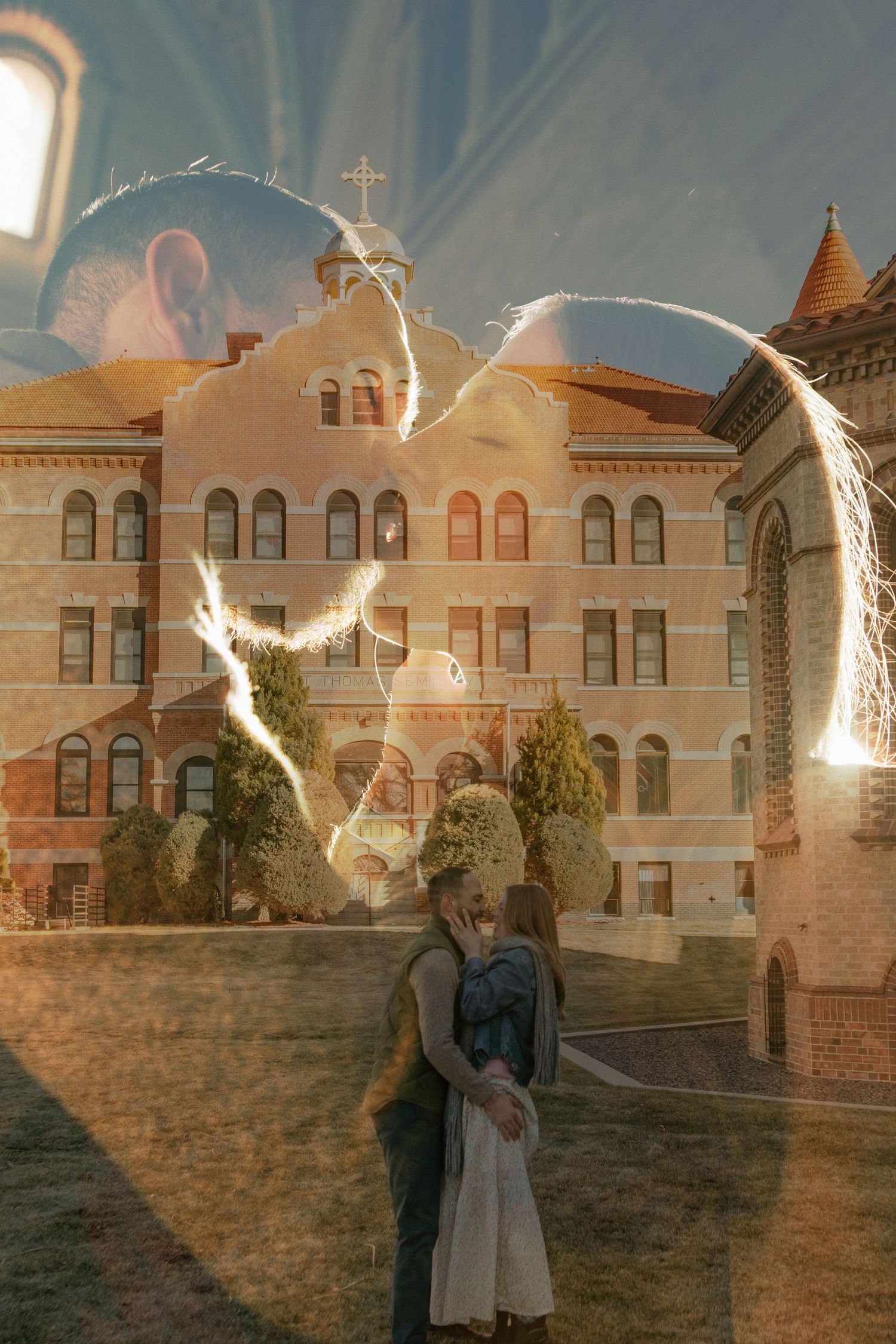 A sparkler creates a glowing heart shape in front of a historic brick building at dusk.