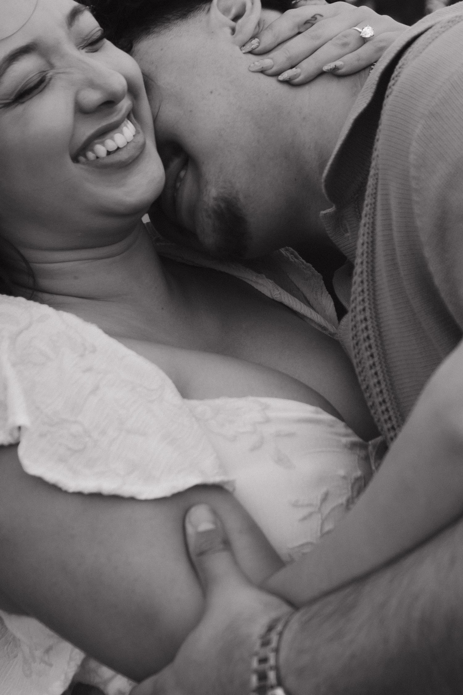 Black and white photo of couple laughing and embracing in a tender, joyful moment.