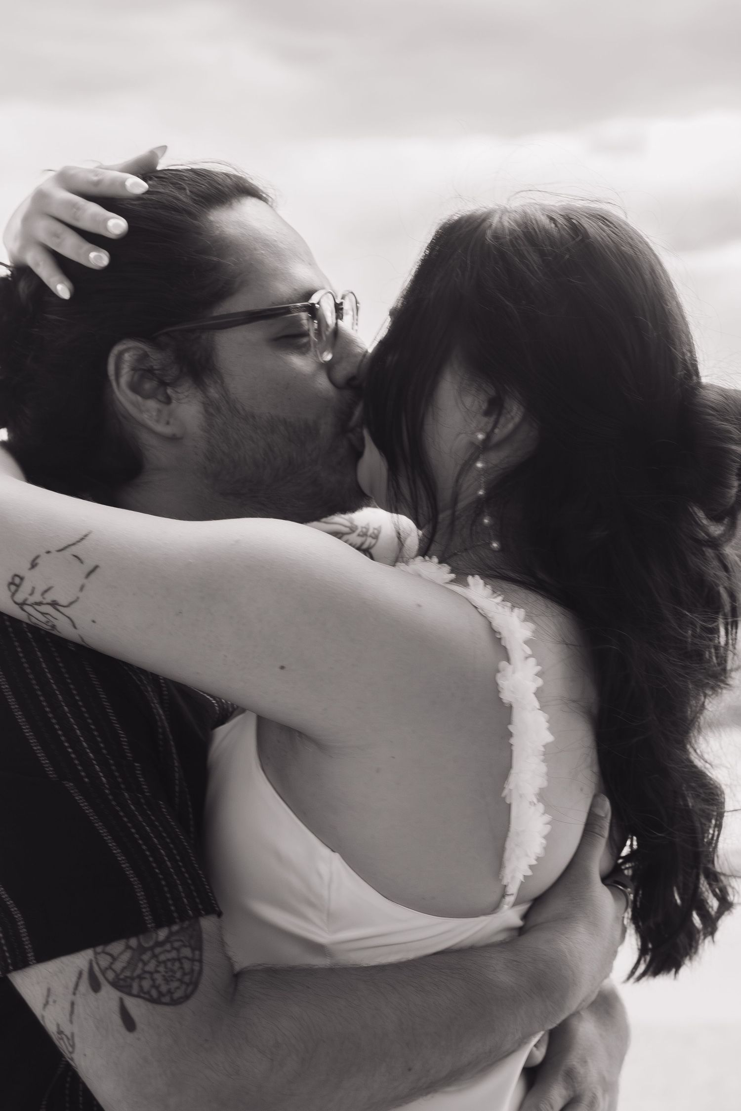 Intimate couple portrait with dramatic lighting shows tender embrace against architectural backdrop.