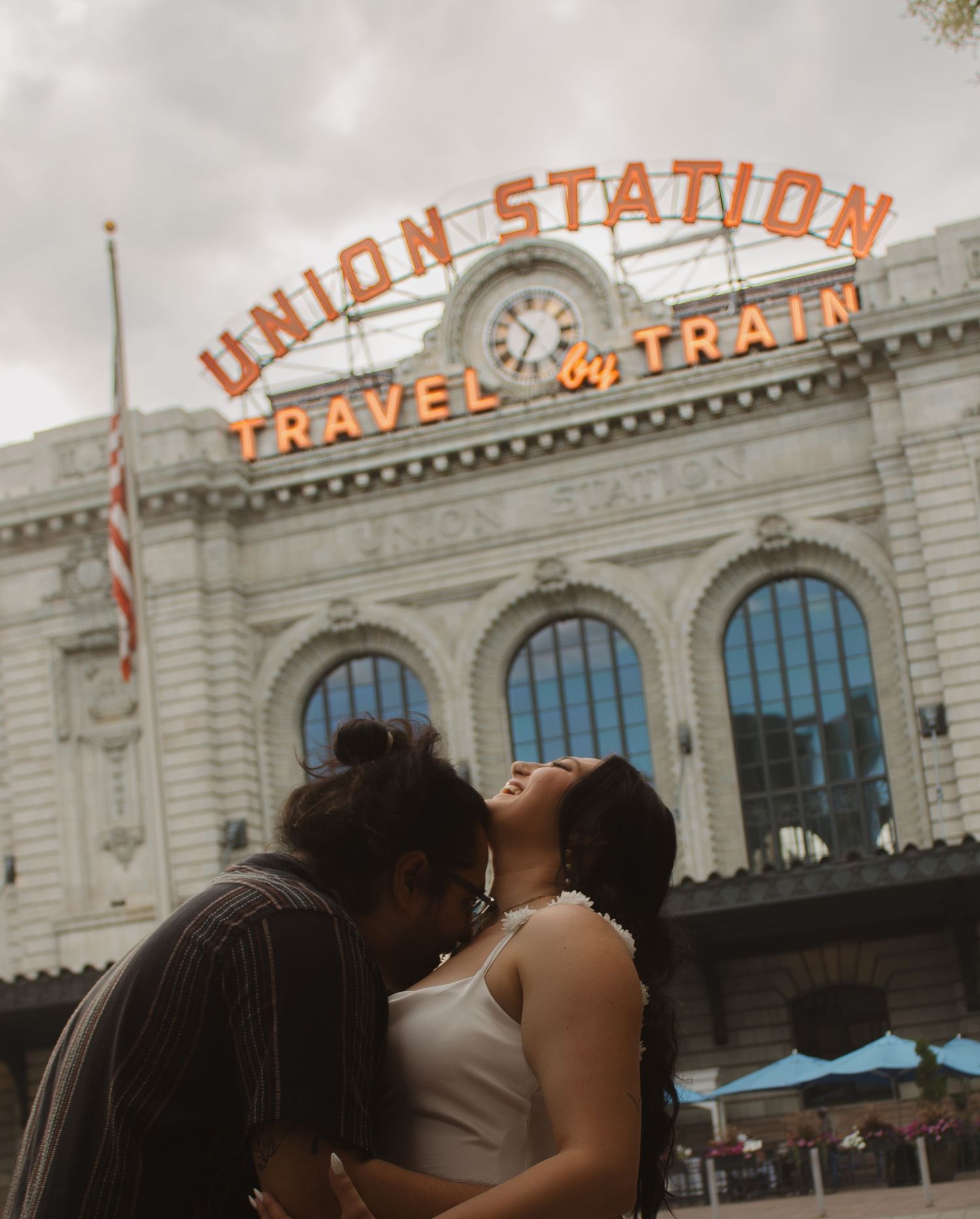 A romantic moment captured outside Union Station with ornate architecture and vintage signage in the background.