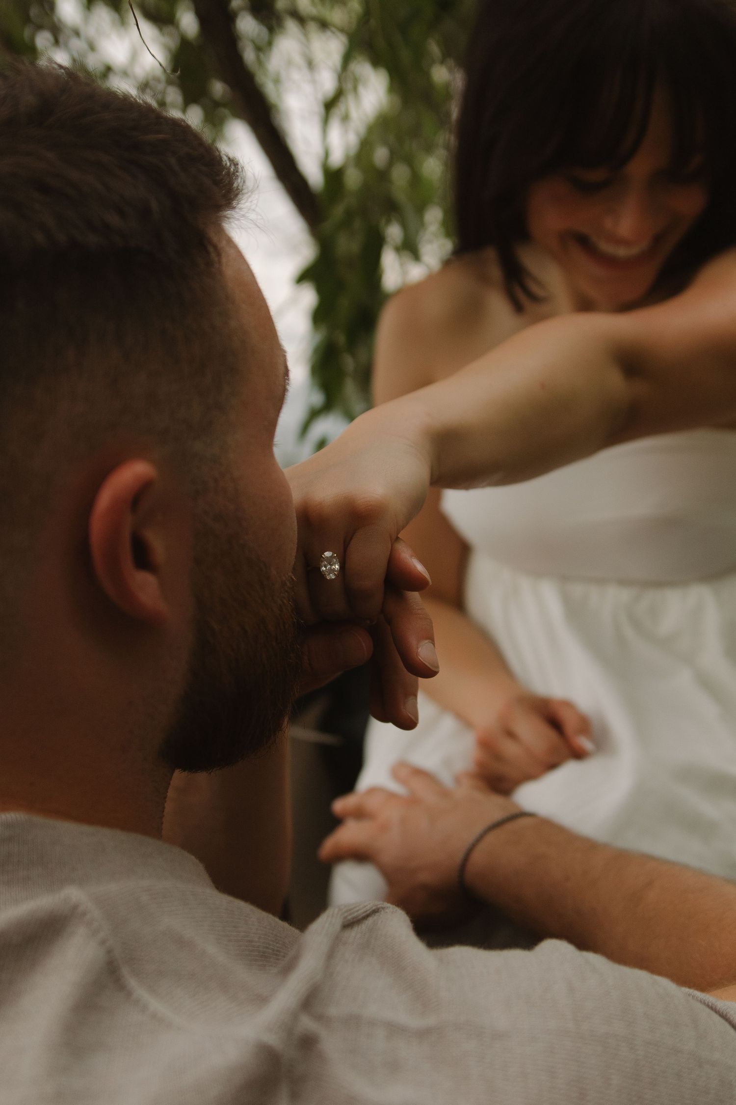 A tender moment captured in soft natural lighting amidst foliage.