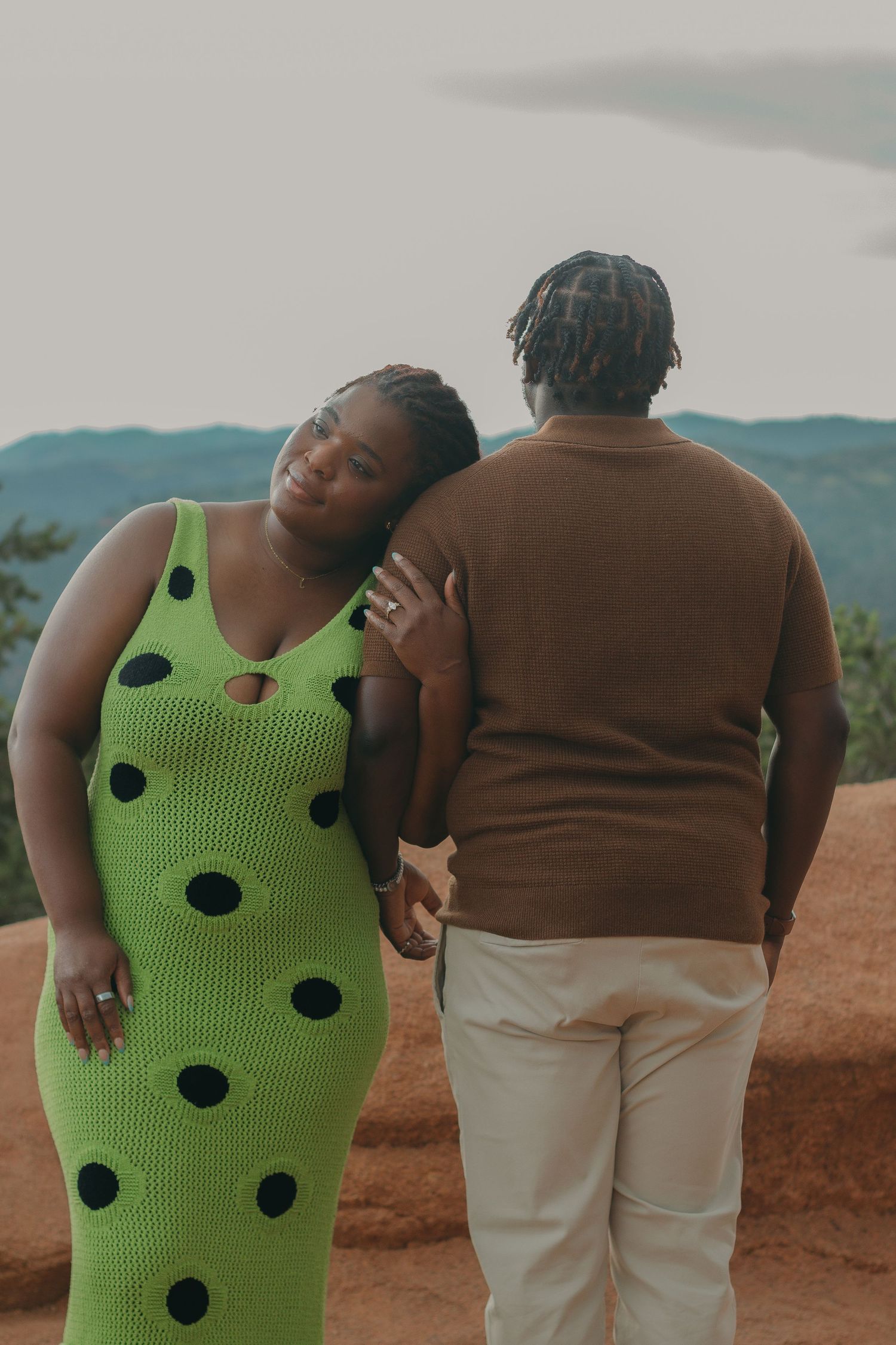 Candid moment of two people embracing while dancing against a mountainous backdrop.
