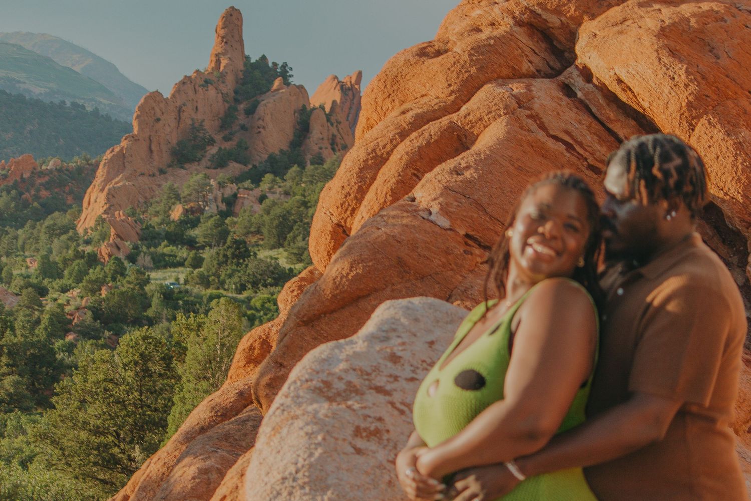 Two people share a loving moment among the iconic red rocks during sunset.