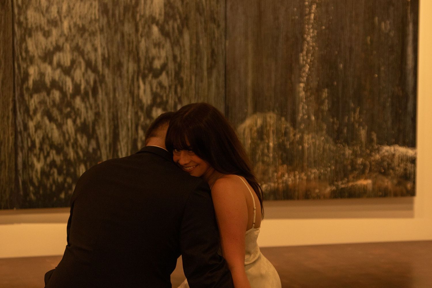 Couple dancing in front of a wall with strong shadows and artistic lighting.