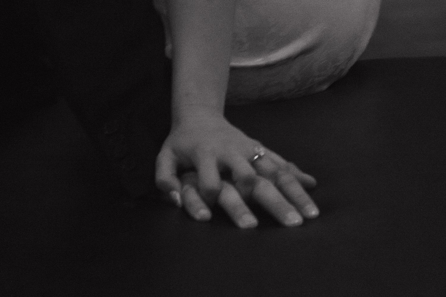 Artistic black and white photo showing hands delicately pressing piano keys during performance.